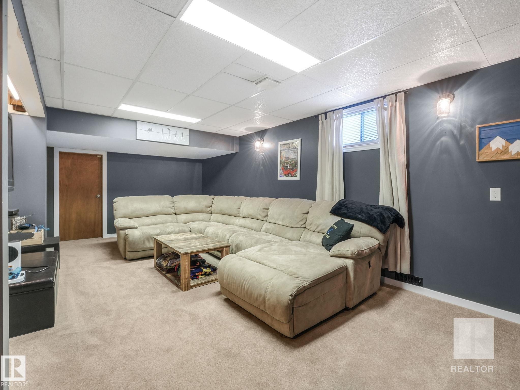 Carpeted living area with a drop ceiling and baseboards - 4504 48 Avenue, Onoway, AB - Indoor Photo Showing Basement