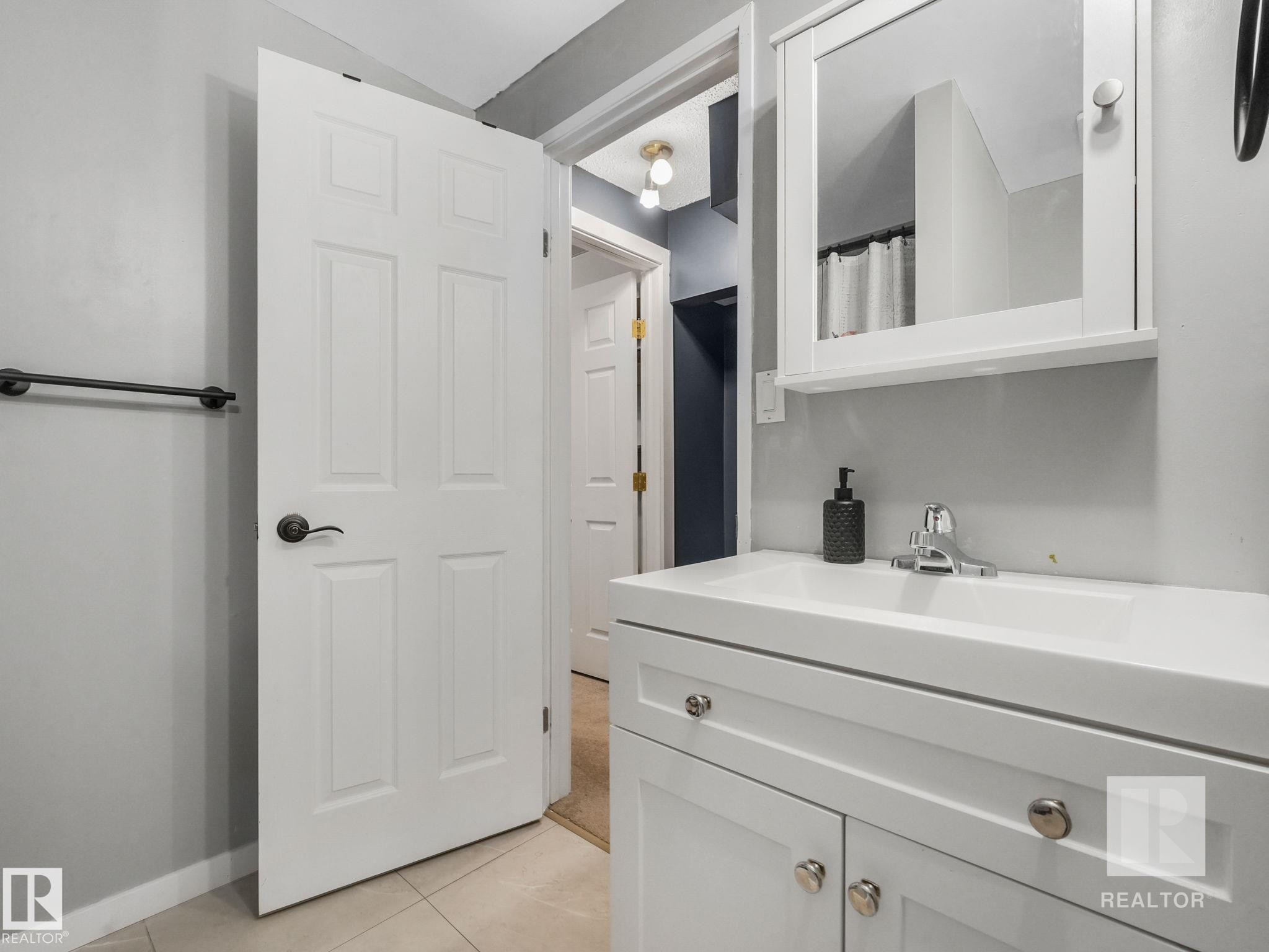 Bathroom featuring a shower with curtain, vanity, and light tile patterned floors - 4504 48 Avenue, Onoway, AB - Indoor Photo Showing Bathroom