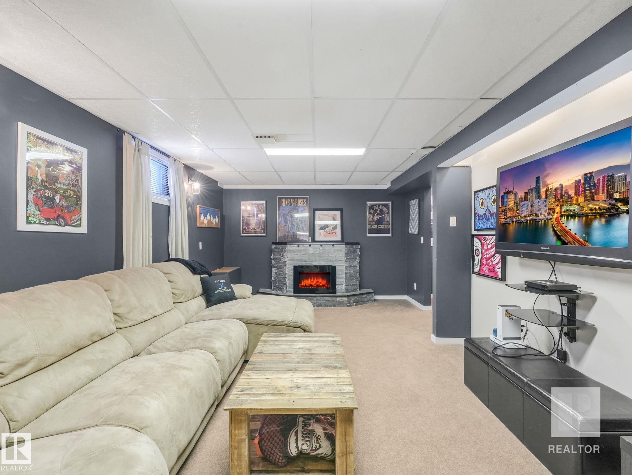 Living area featuring a drop ceiling, light carpet, and a stone fireplace - 4504 48 Avenue, Onoway, AB - Indoor With Fireplace