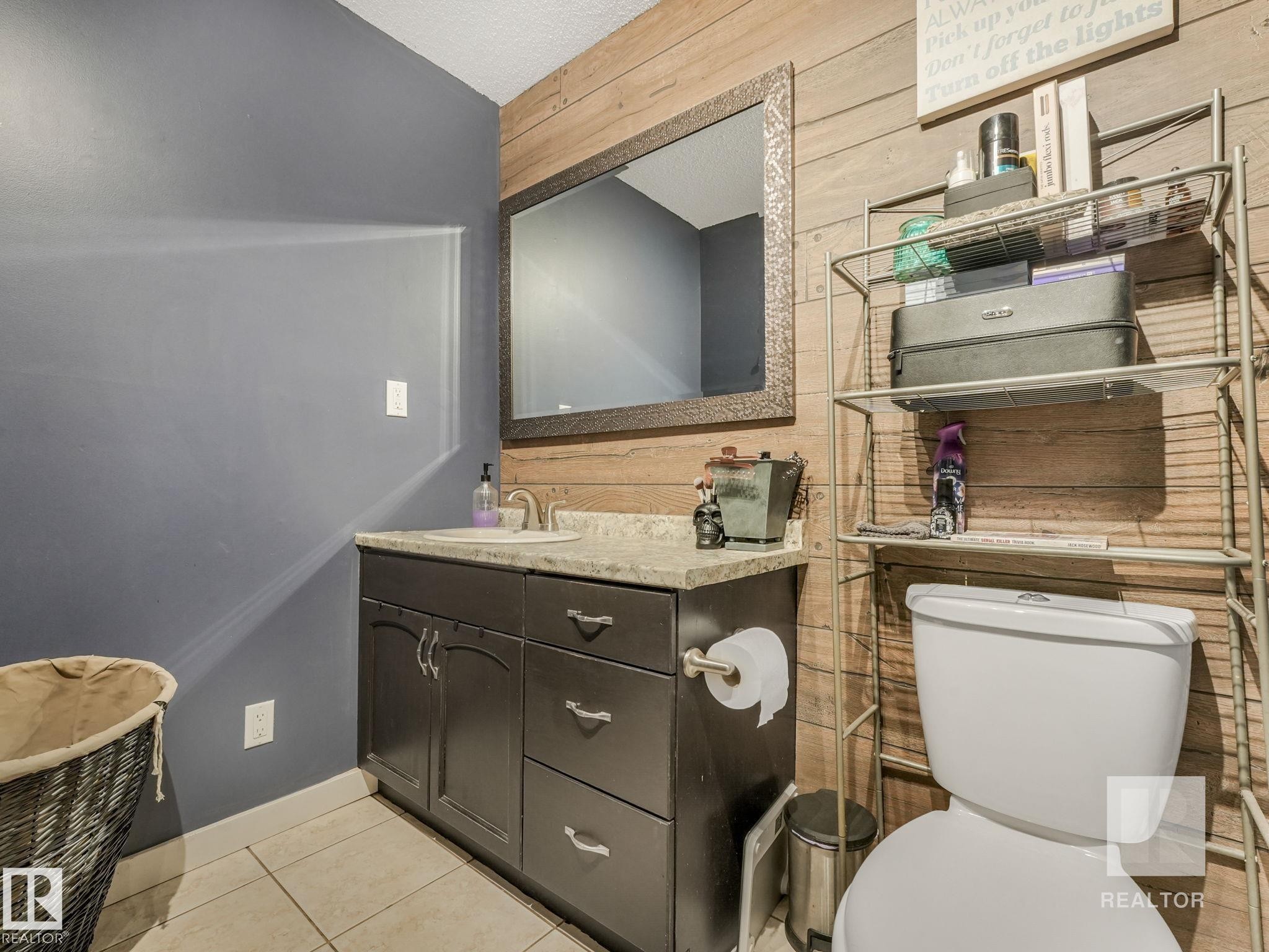 Bathroom featuring vanity, light tile patterned floors, and wood walls - 4504 48 Avenue, Onoway, AB - Indoor Photo Showing Bathroom