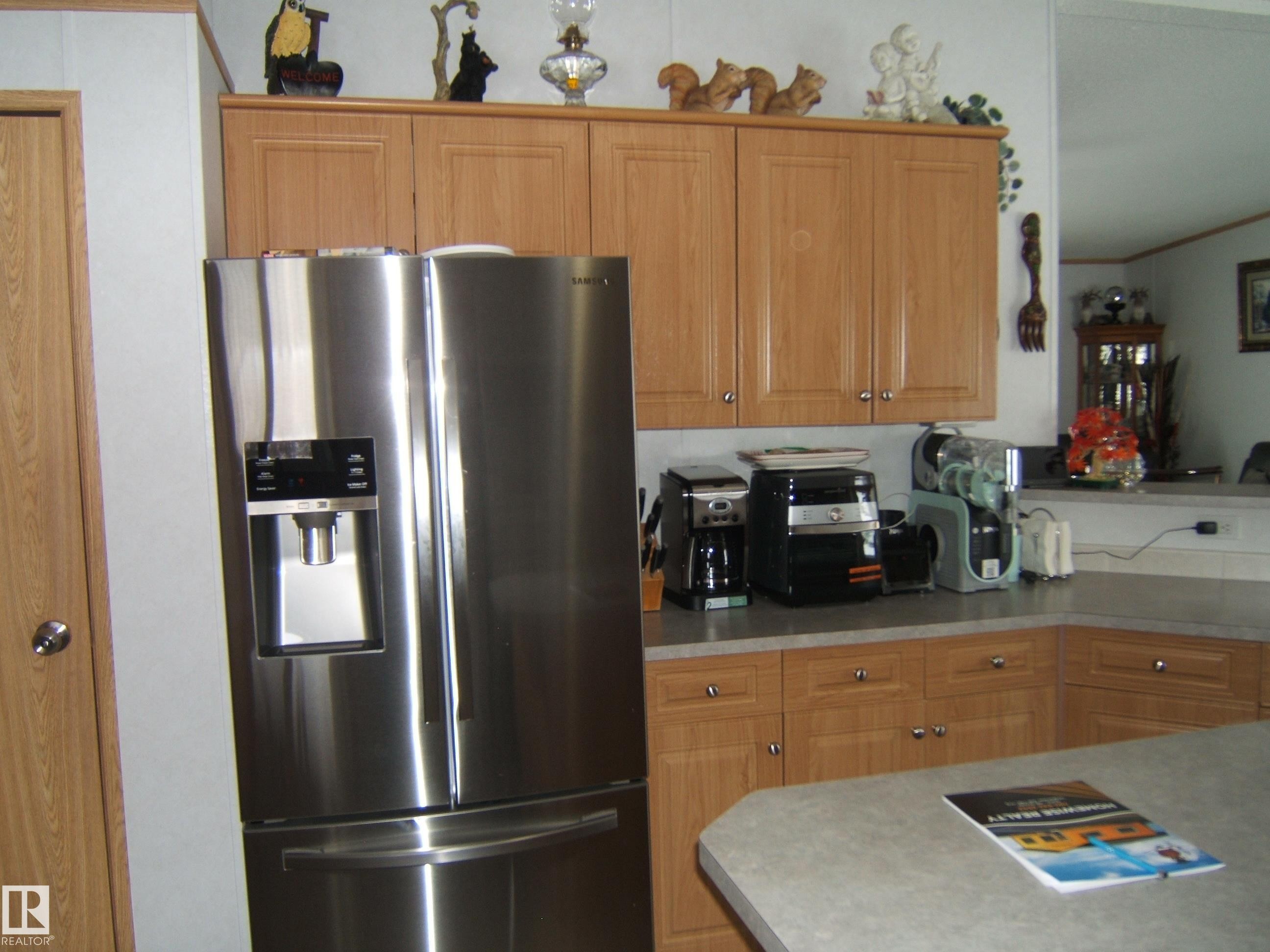 Kitchen featuring stainless steel refrigerator with ice dispenser, light countertops, and wood finish cabinets - 125076 Twp Rd 540, Rural Two Hills County, AB - Indoor Photo Showing Kitchen