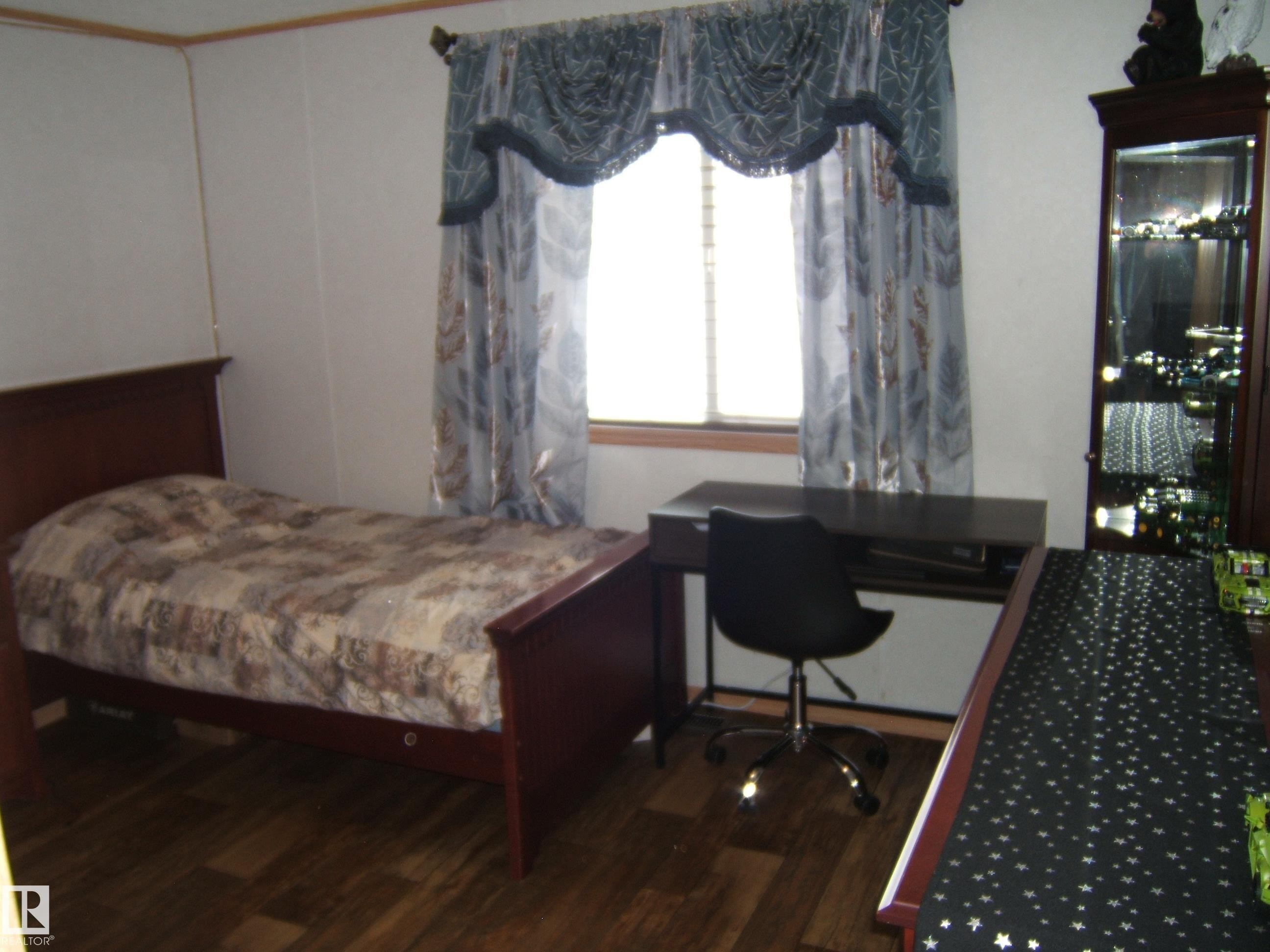 Bedroom with dark wood finished floors and an office area - 125076 Twp Rd 540, Rural Two Hills County, AB - Indoor Photo Showing Bedroom