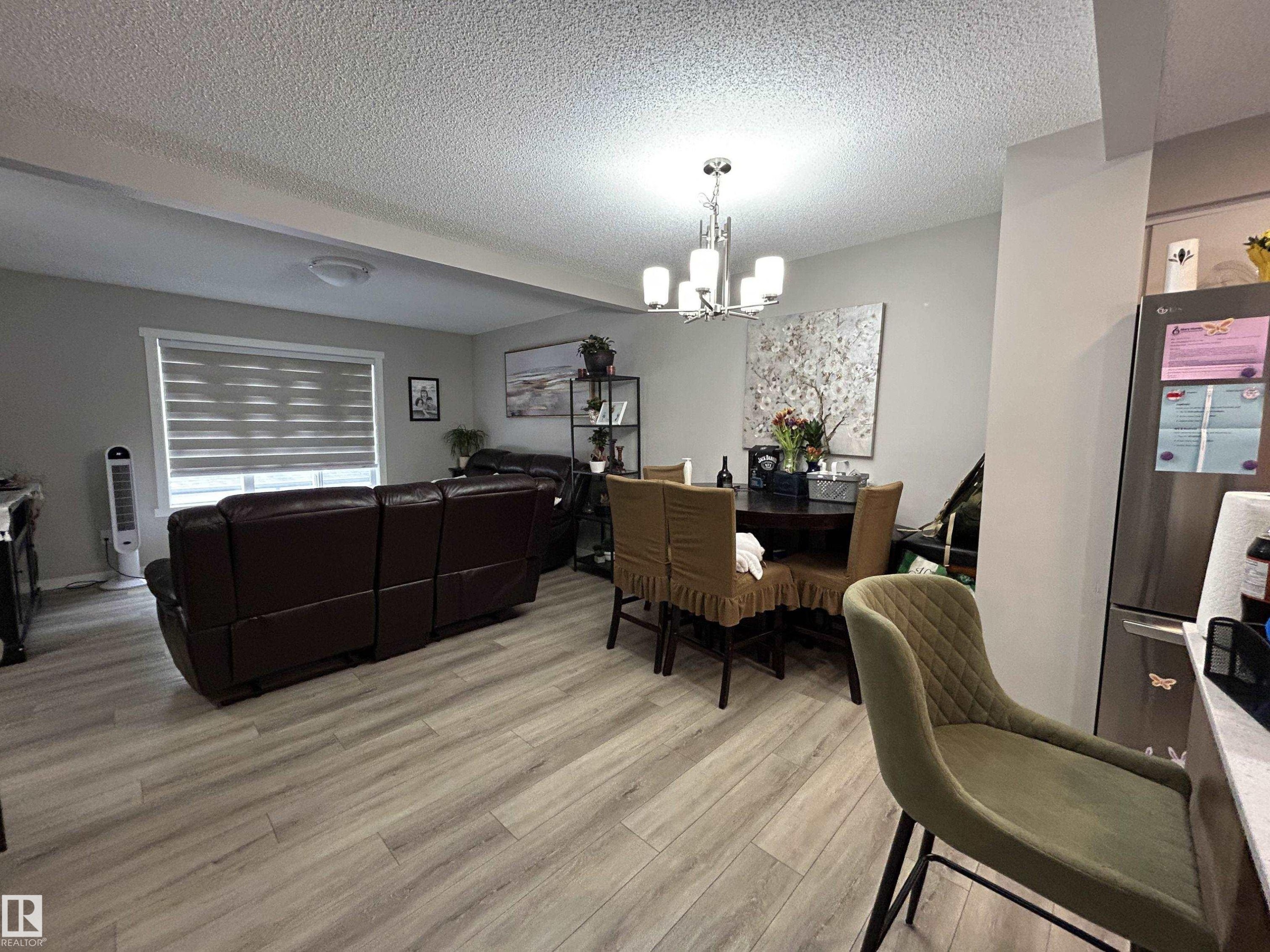 Dining room with a textured ceiling, light wood-style floors, and a chandelier - 120 1530 Tamarack Boulevard, Edmonton, AB - Indoor
