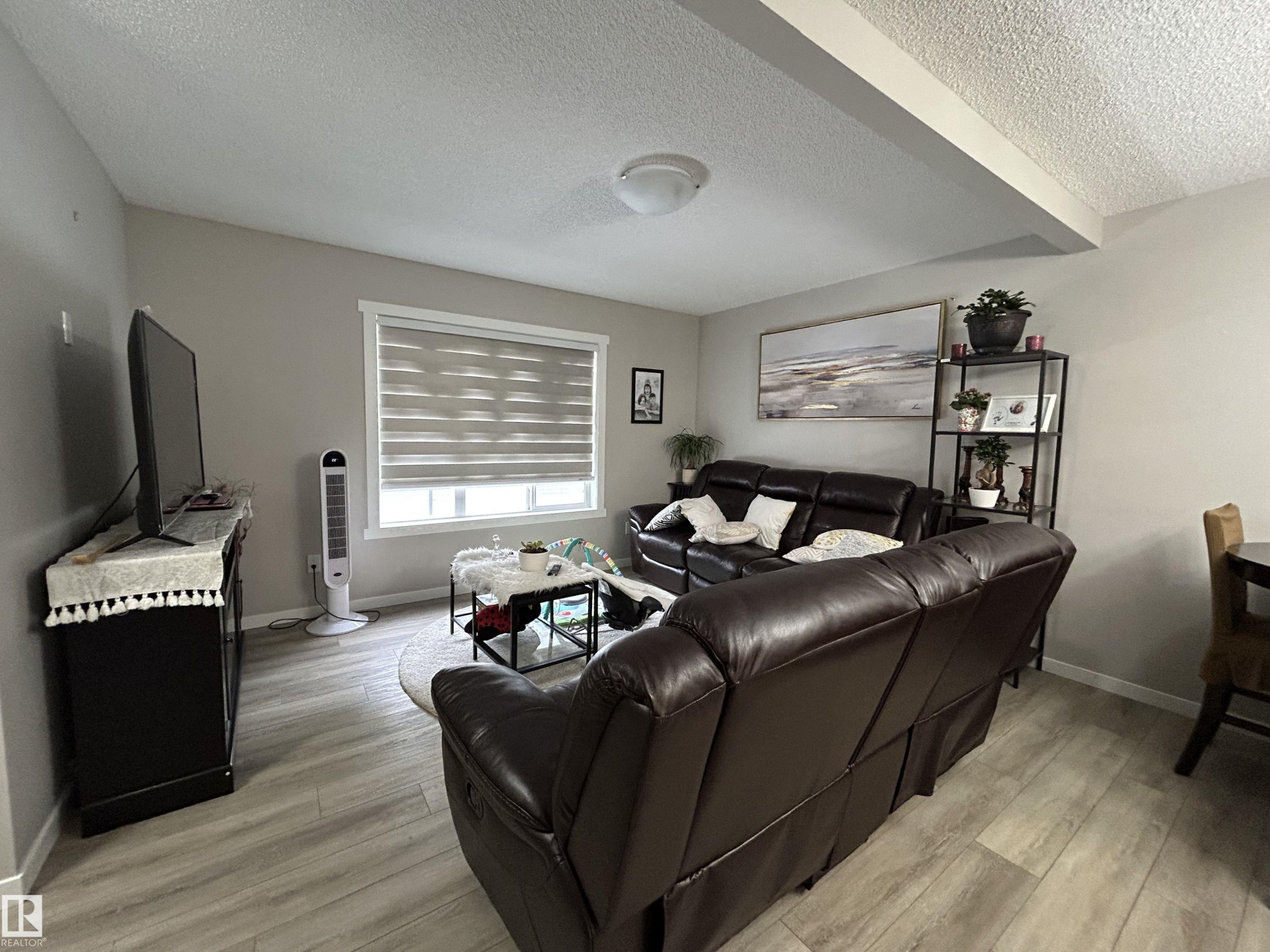 Living area featuring a textured ceiling, light wood-style flooring, and beam ceiling - 120 1530 Tamarack Boulevard, Edmonton, AB - Indoor