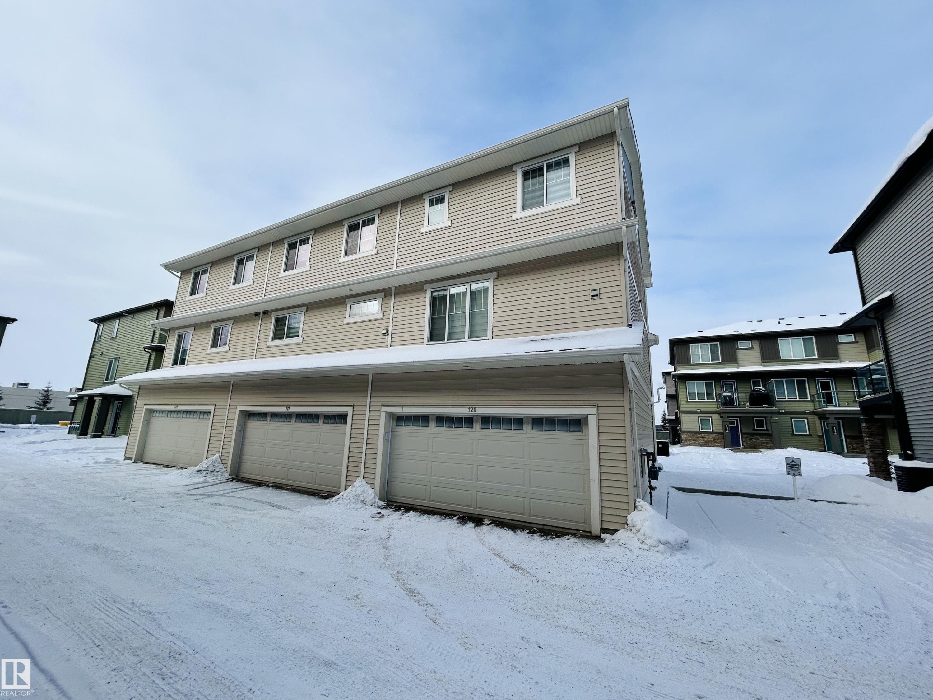 Snow covered rear of property featuring a garage - 120 1530 Tamarack Boulevard, Edmonton, AB - Outdoor