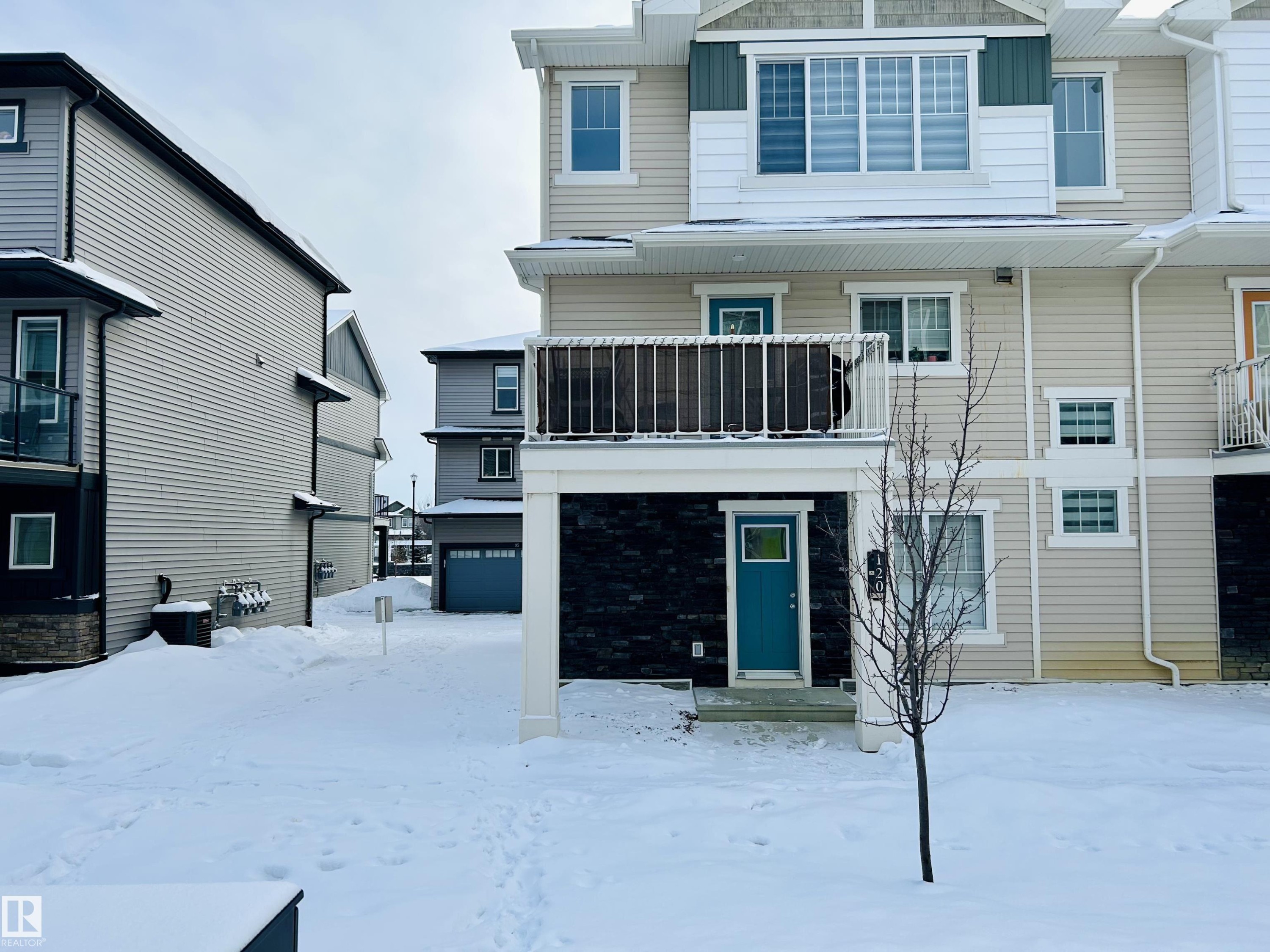 Snow covered rear of property with board and batten siding and a balcony - 120 1530 Tamarack Boulevard, Edmonton, AB - Outdoor With Facade
