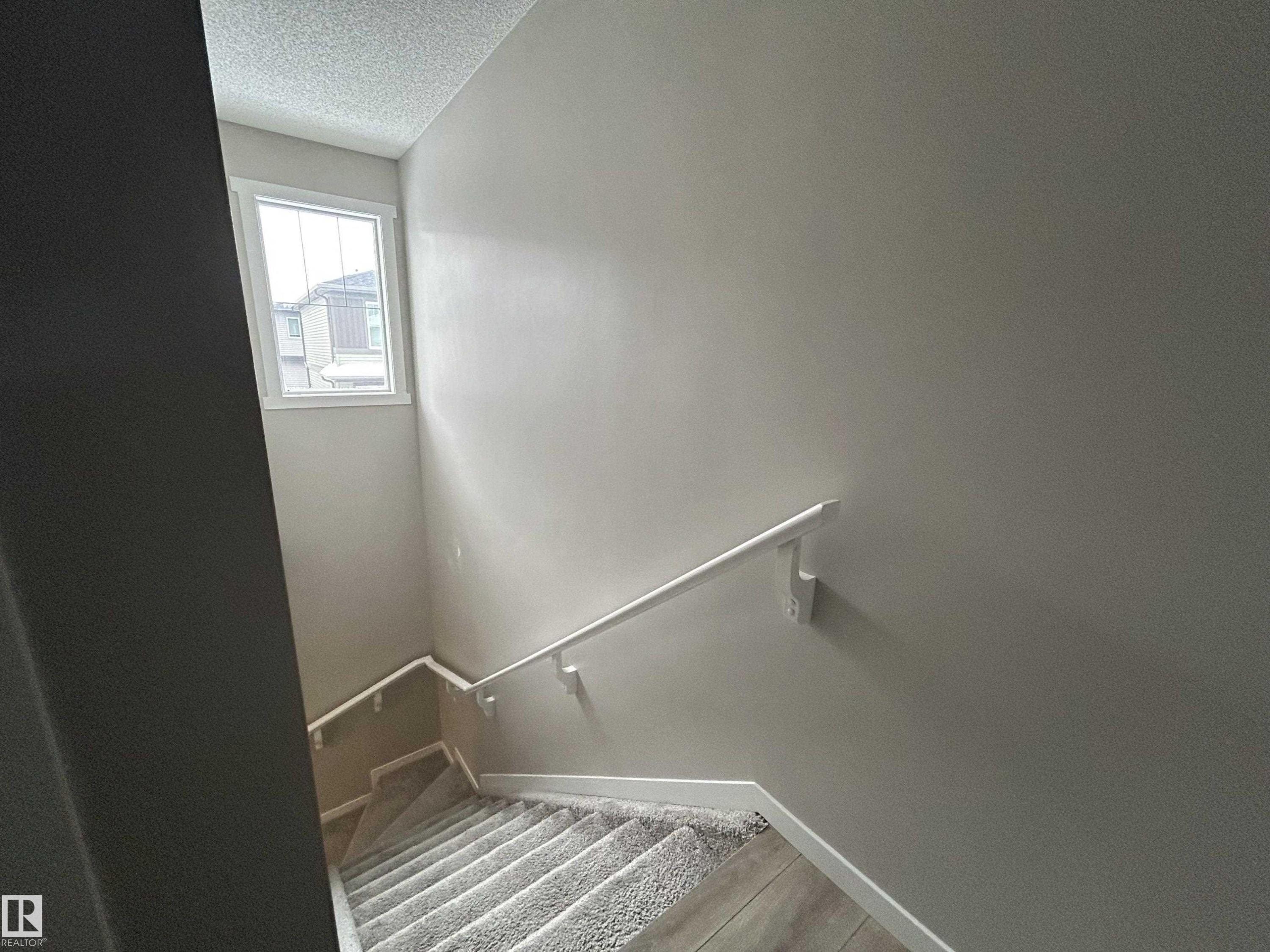 Staircase featuring a textured ceiling and baseboards - 120 1530 Tamarack Boulevard, Edmonton, AB - Indoor