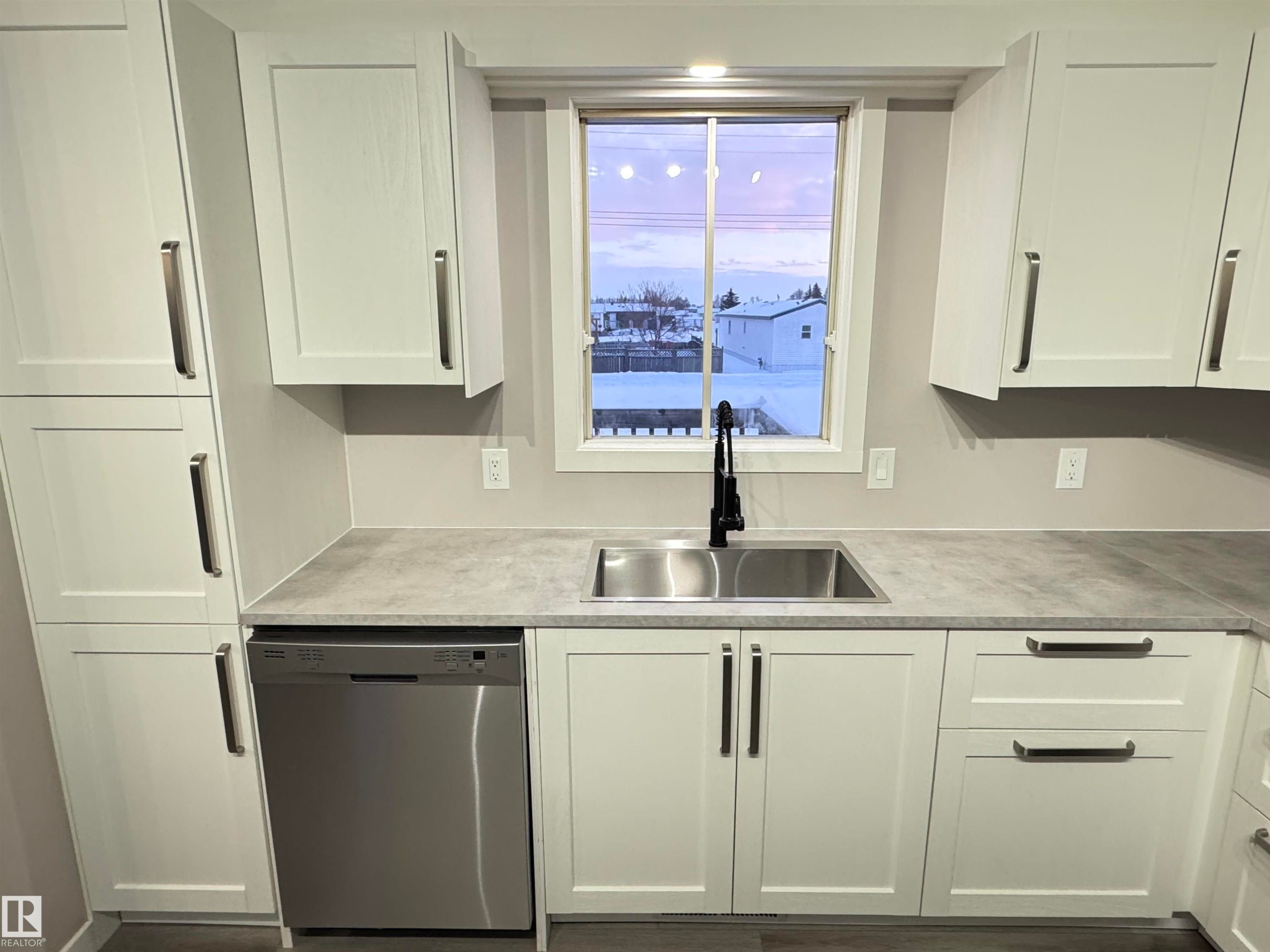 Kitchen featuring white cabinetry, dishwasher, and light countertops - 4919 49 Avenue, Vimy, AB - Indoor Photo Showing Kitchen
