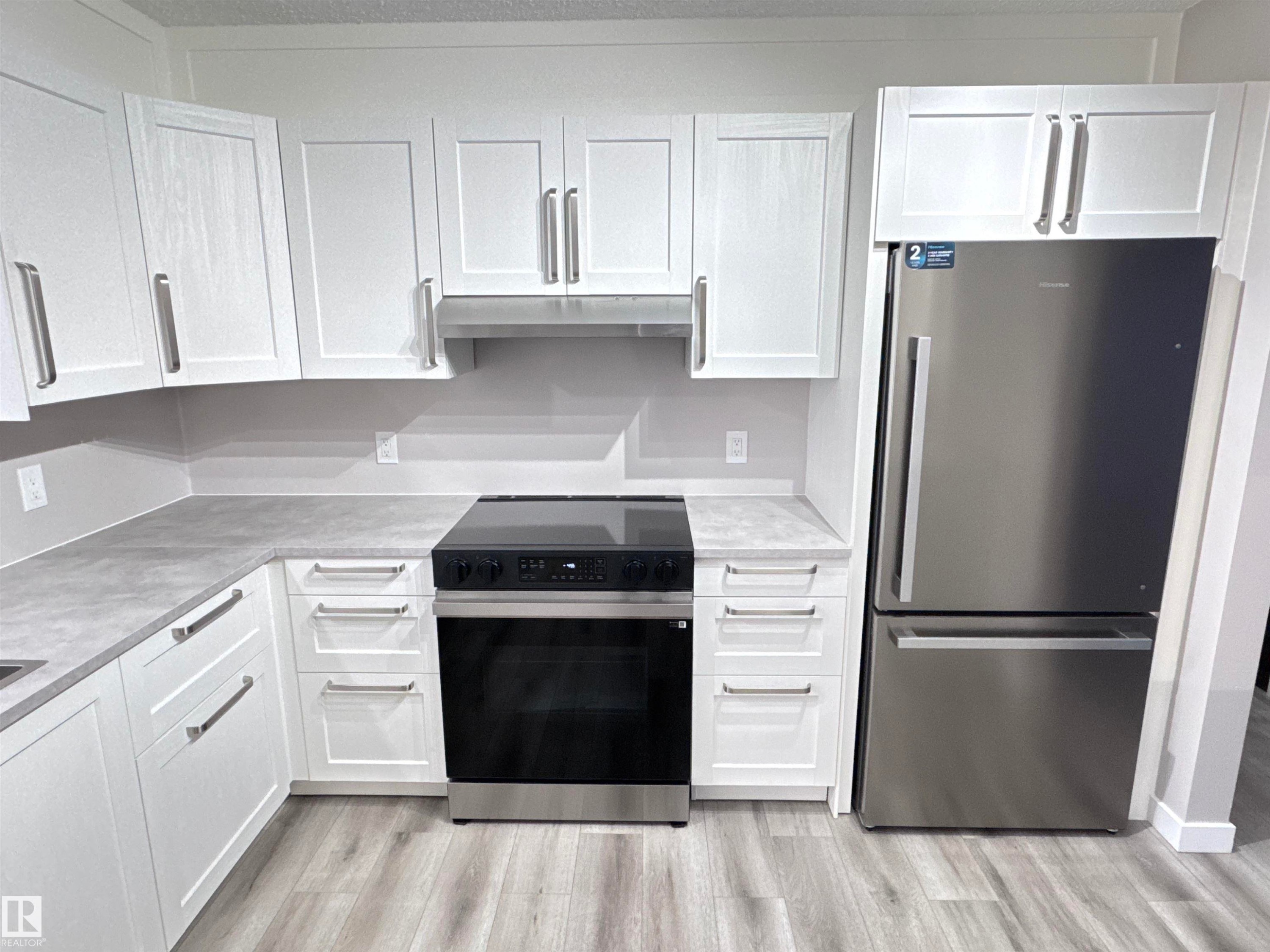 Kitchen with freestanding refrigerator, range with electric cooktop, white cabinets, and light wood-style flooring - 4919 49 Avenue, Vimy, AB - Indoor Photo Showing Kitchen