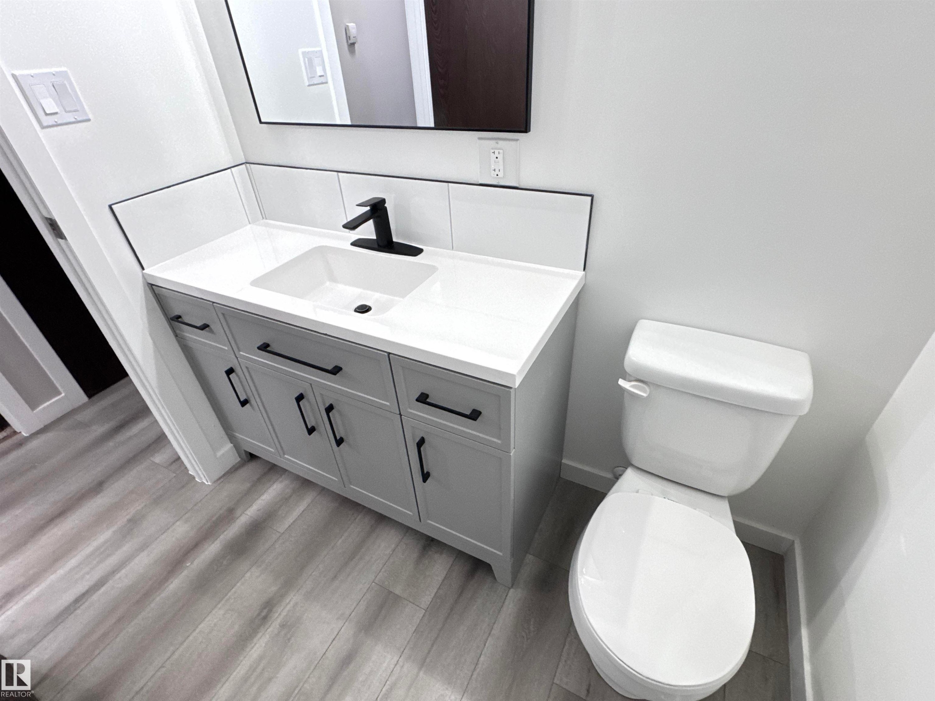 Half bath with vanity and light wood-style flooring - 4919 49 Avenue, Vimy, AB - Indoor Photo Showing Bathroom