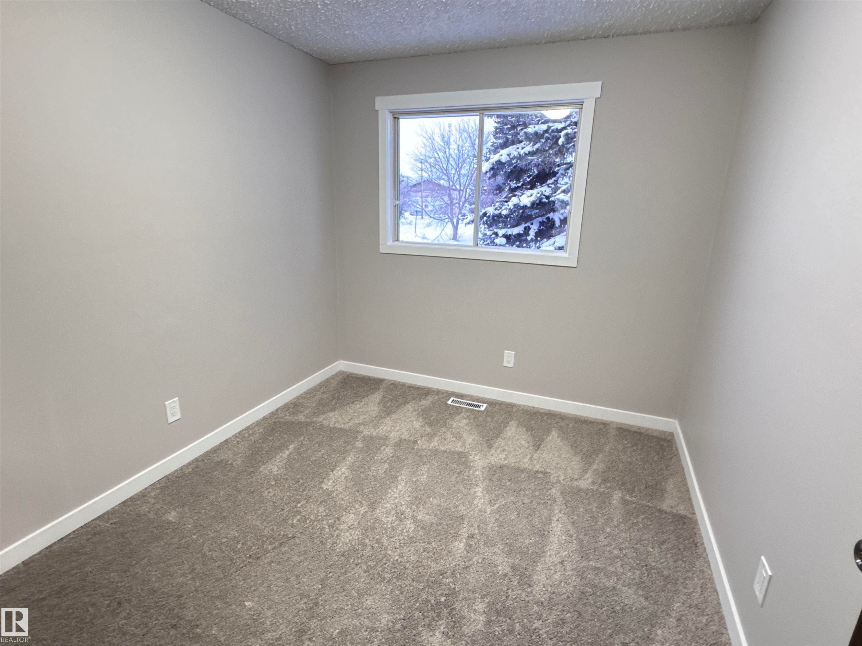 Carpeted empty room with baseboards and a textured ceiling - 4919 49 Avenue, Vimy, AB - Indoor Photo Showing Other Room