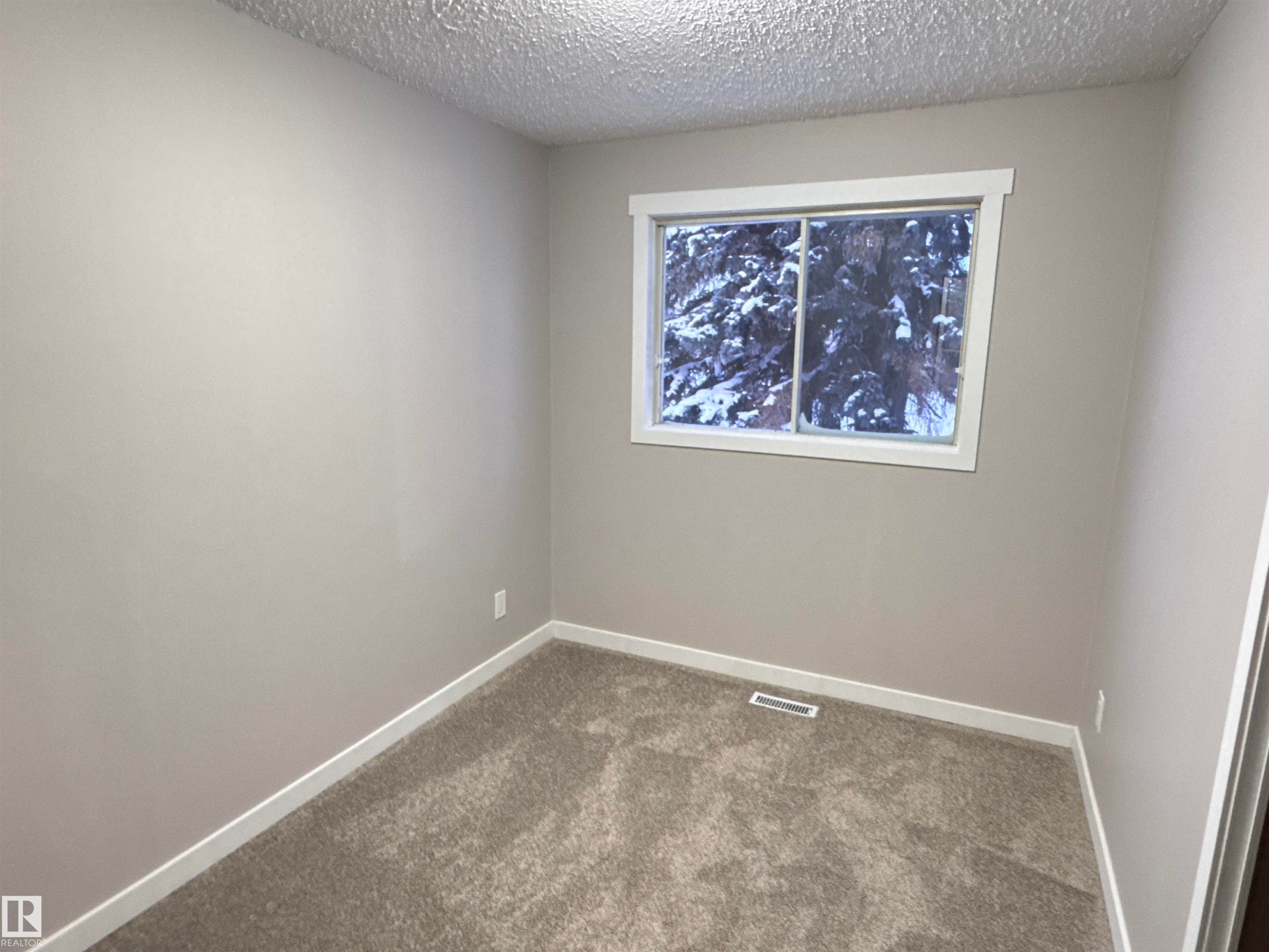 Spare room featuring carpet flooring and a textured ceiling - 4919 49 Avenue, Vimy, AB - Indoor Photo Showing Other Room