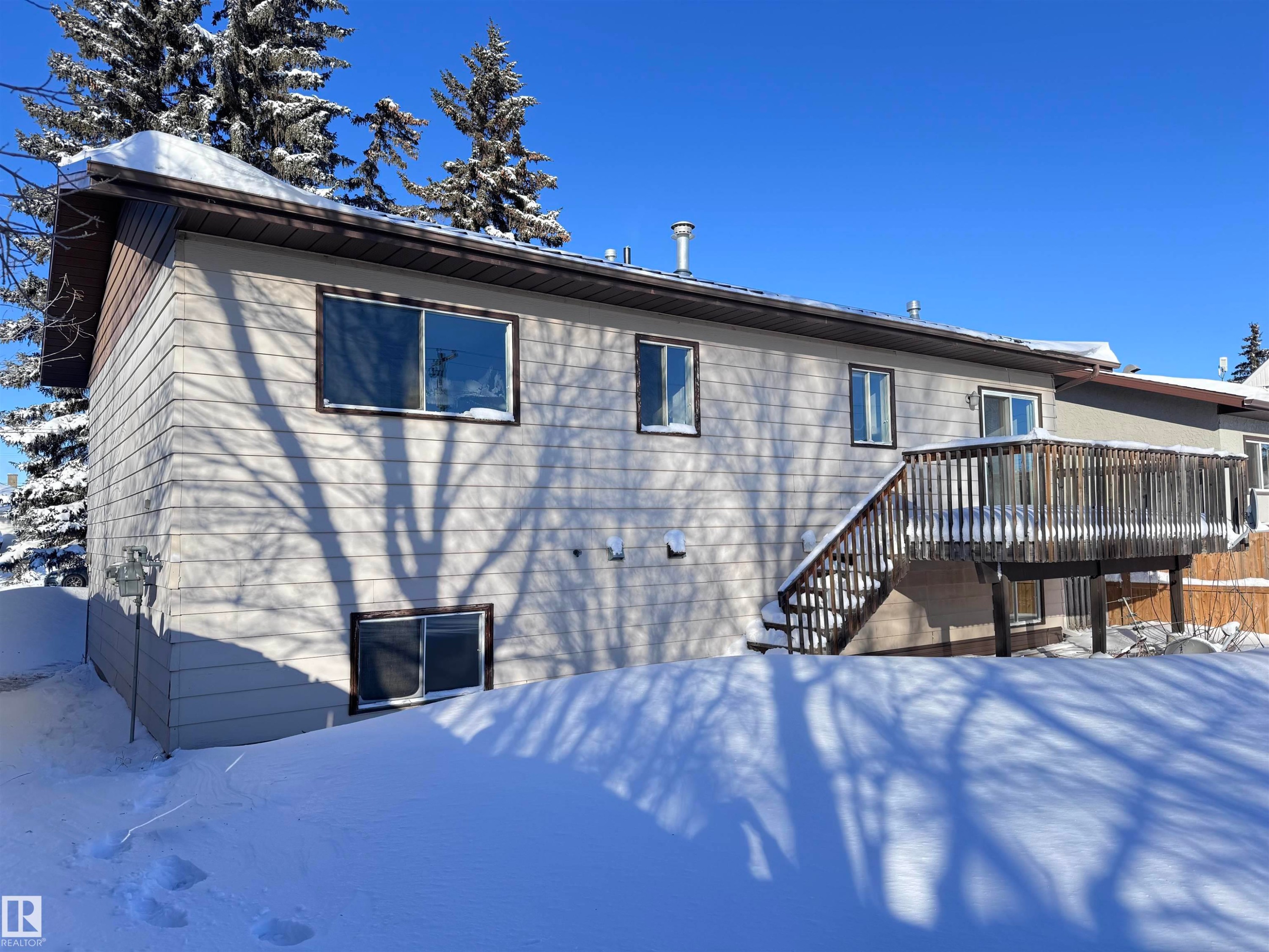 Snow covered rear of property featuring a wooden deck and stairway - 4919 49 Avenue, Vimy, AB - Outdoor