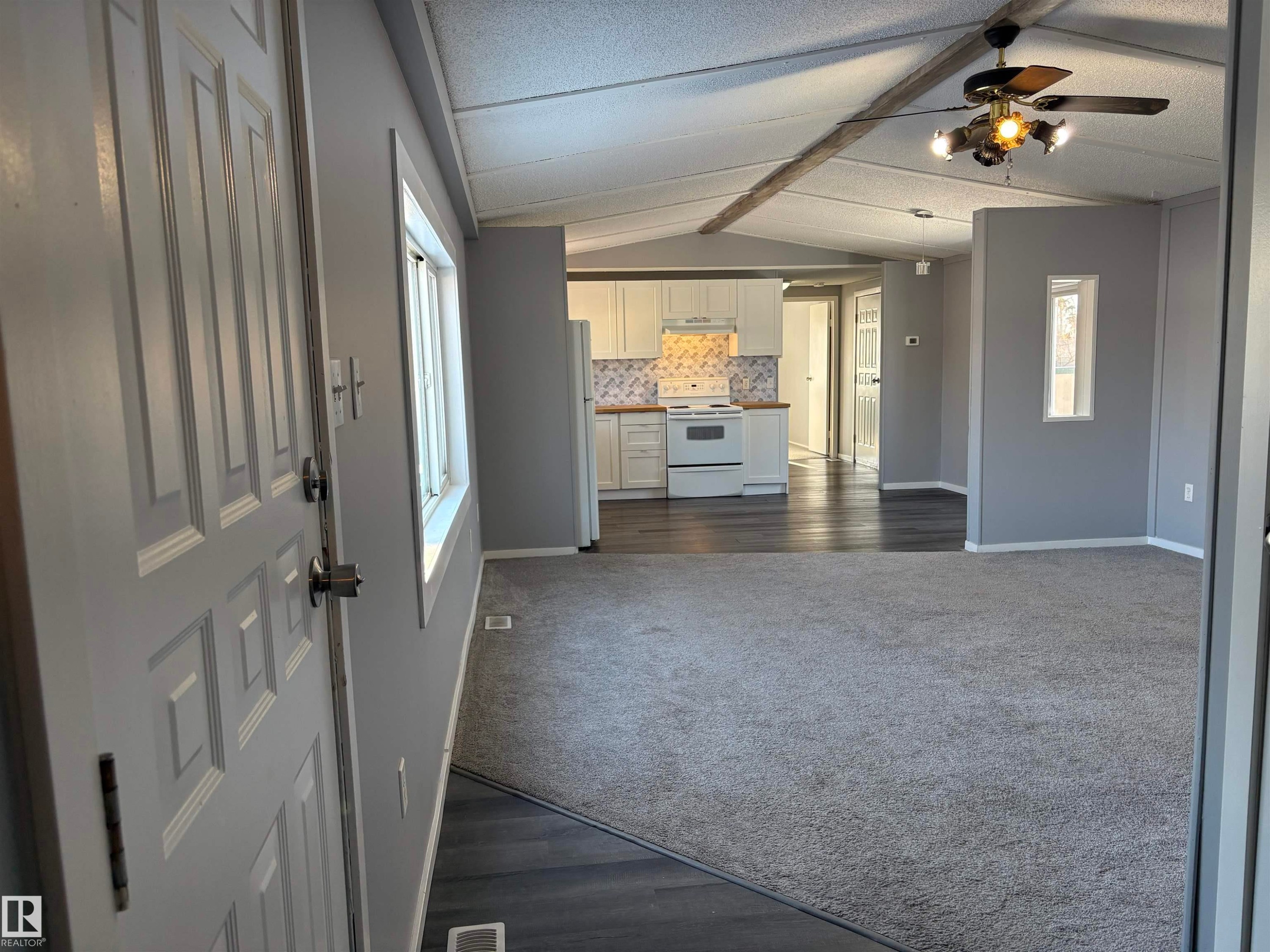 Unfurnished living room with dark wood-type flooring, beam ceiling, ceiling fan, and dark colored carpet - 8 Evergreen Park Drive, Edmonton, AB - Indoor Photo Showing Other Room