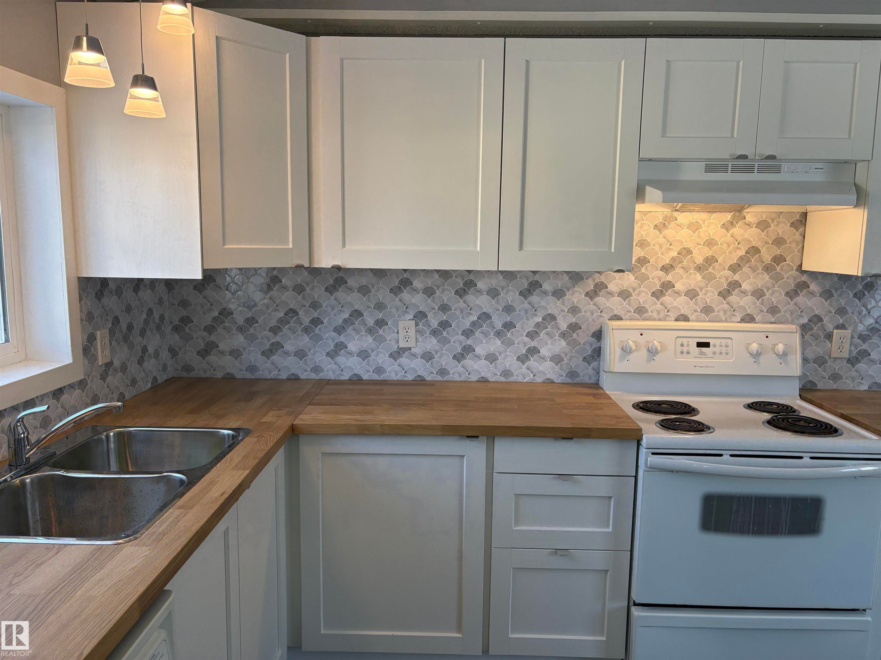Kitchen featuring white range with electric stovetop, wood counters, hanging light fixtures, and tasteful backsplash - 8 Evergreen Park Drive, Edmonton, AB - Indoor Photo Showing Kitchen With Double Sink