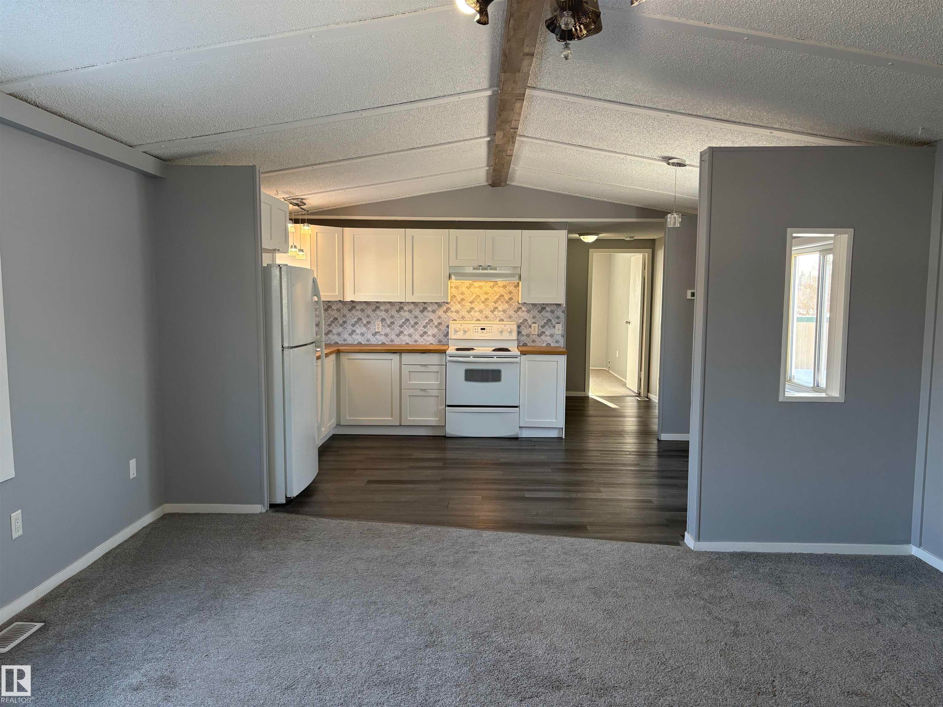 Kitchen with open floor plan, white cabinets, white appliances, decorative backsplash, and dark carpet - 8 Evergreen Park Drive, Edmonton, AB - Indoor Photo Showing Kitchen