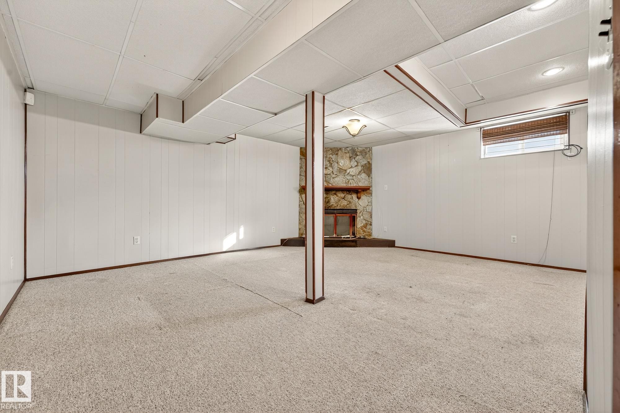 Below grade area featuring wooden walls, carpet, a fireplace, and a paneled ceiling - 4645 115 Avenue, Edmonton, AB - Indoor Photo Showing Other Room