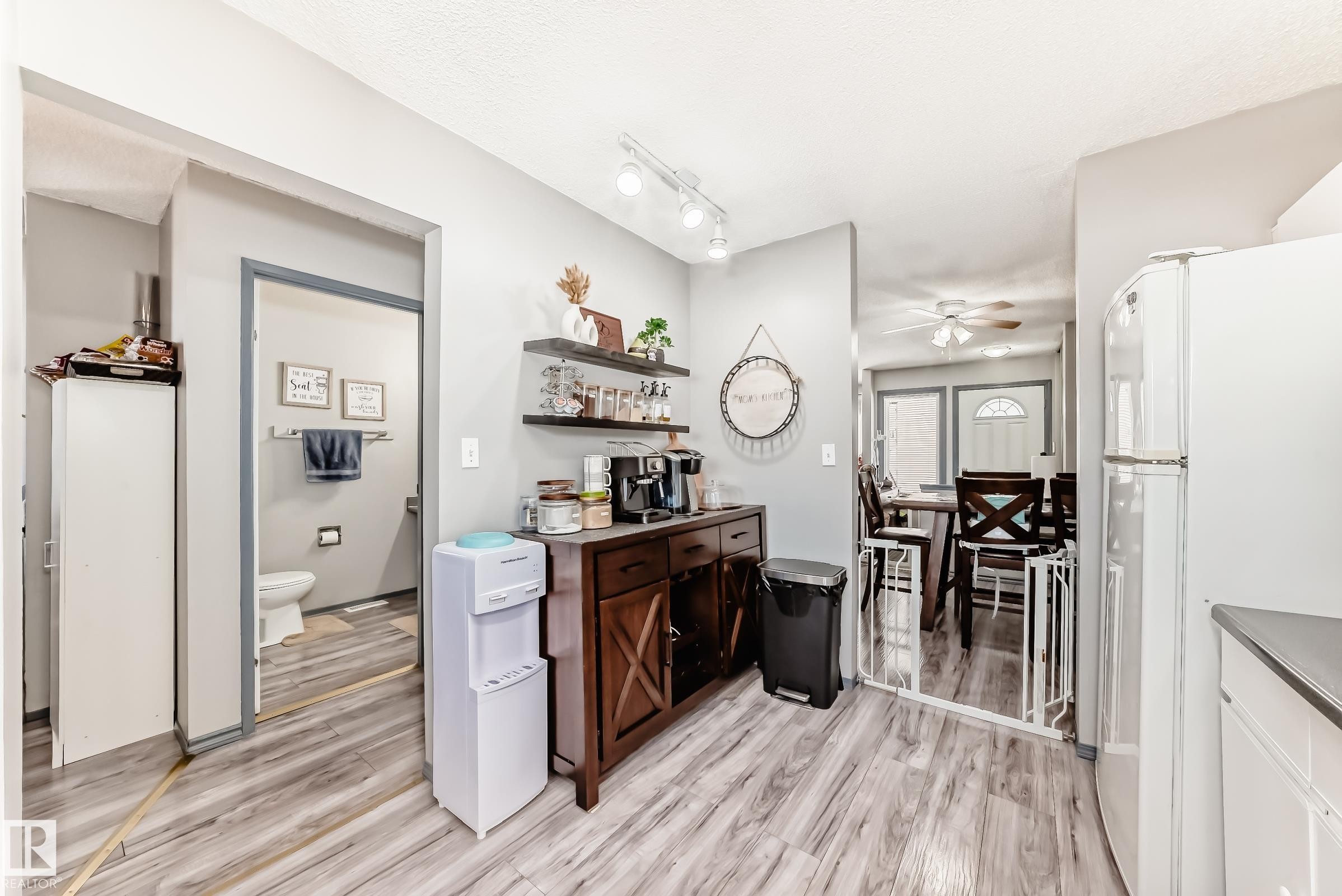Kitchen with freestanding refrigerator, open shelves, light wood finished floors, ceiling fan, and dark countertops - 214A Warwick Road, Edmonton, AB - Indoor Photo Showing Other Room