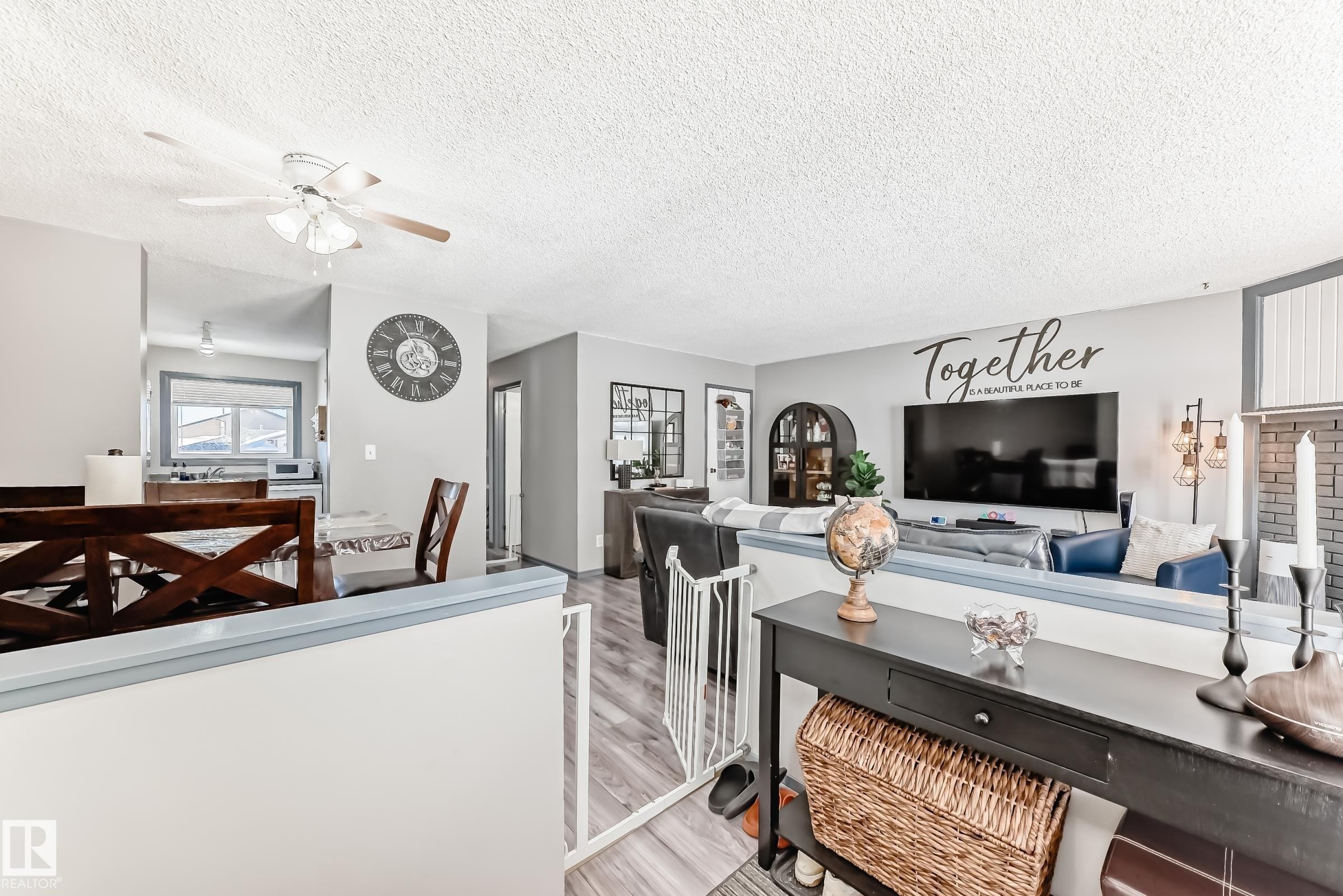 Living area with a ceiling fan, a textured ceiling, and light wood-style flooring - 214A Warwick Road, Edmonton, AB - Indoor Photo Showing Living Room