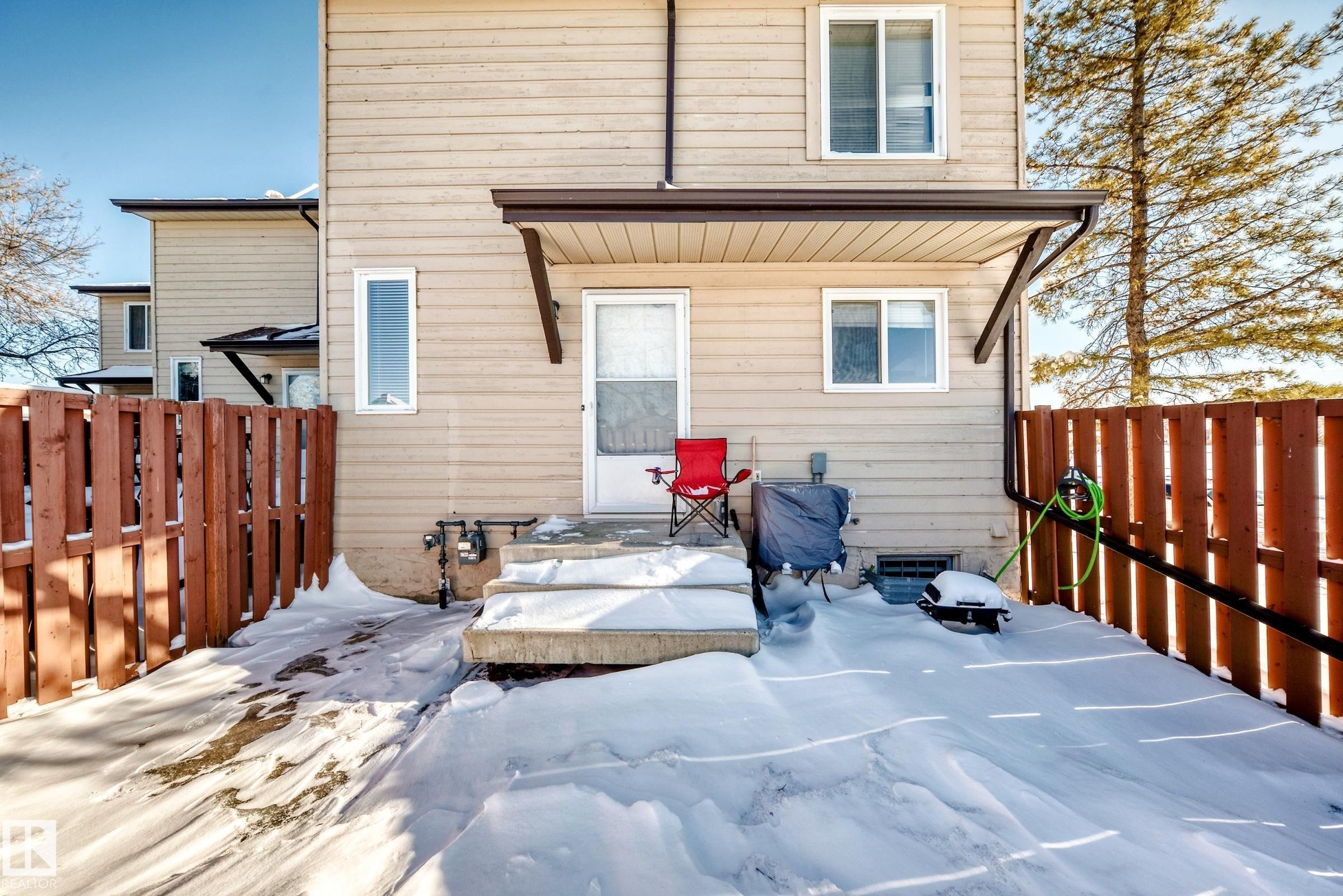 Snow covered rear of property with a fenced backyard - 214A Warwick Road, Edmonton, AB - Outdoor With Exterior