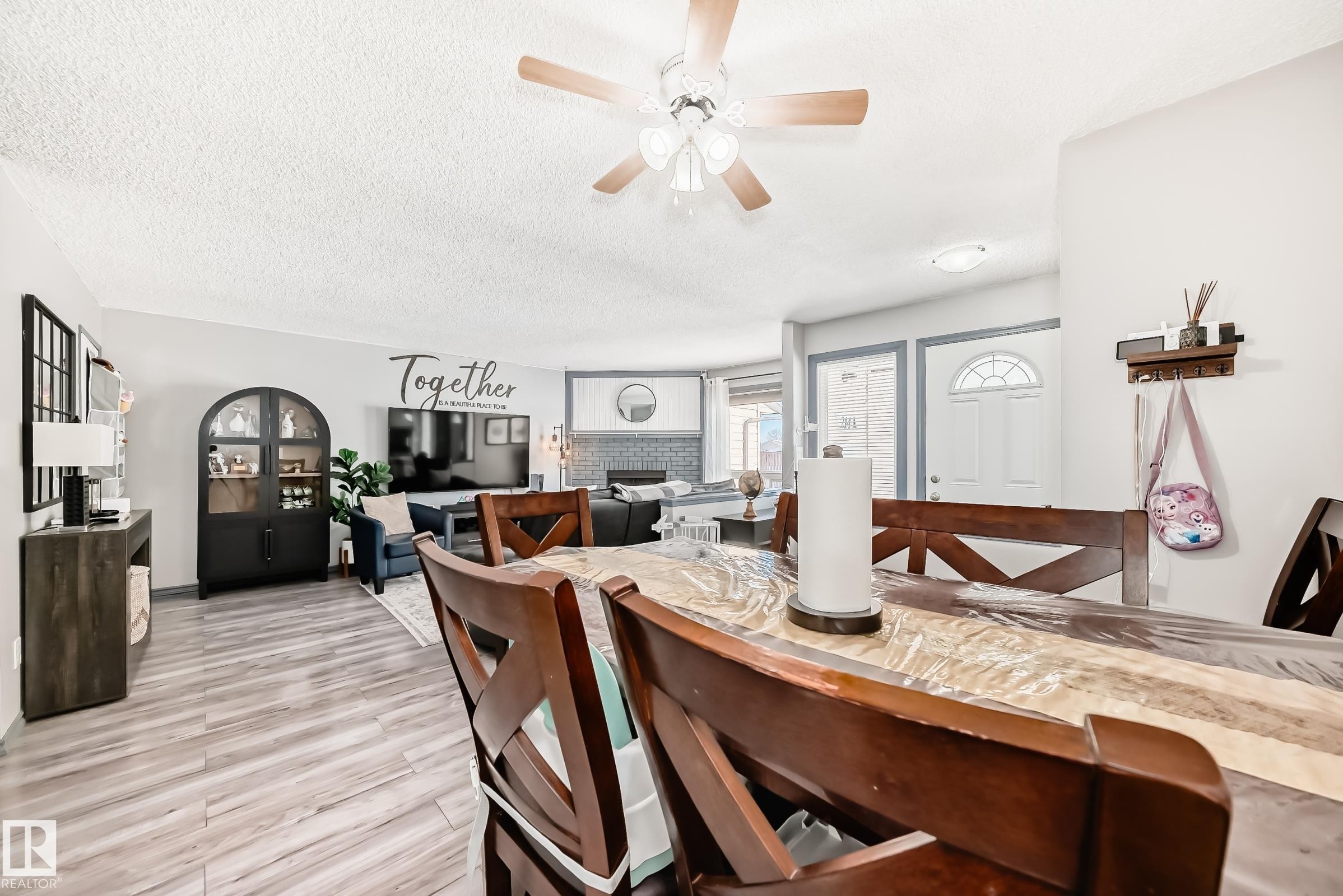 Dining area featuring a ceiling fan, light wood-style floors, and a textured ceiling - 214A Warwick Road, Edmonton, AB - Indoor