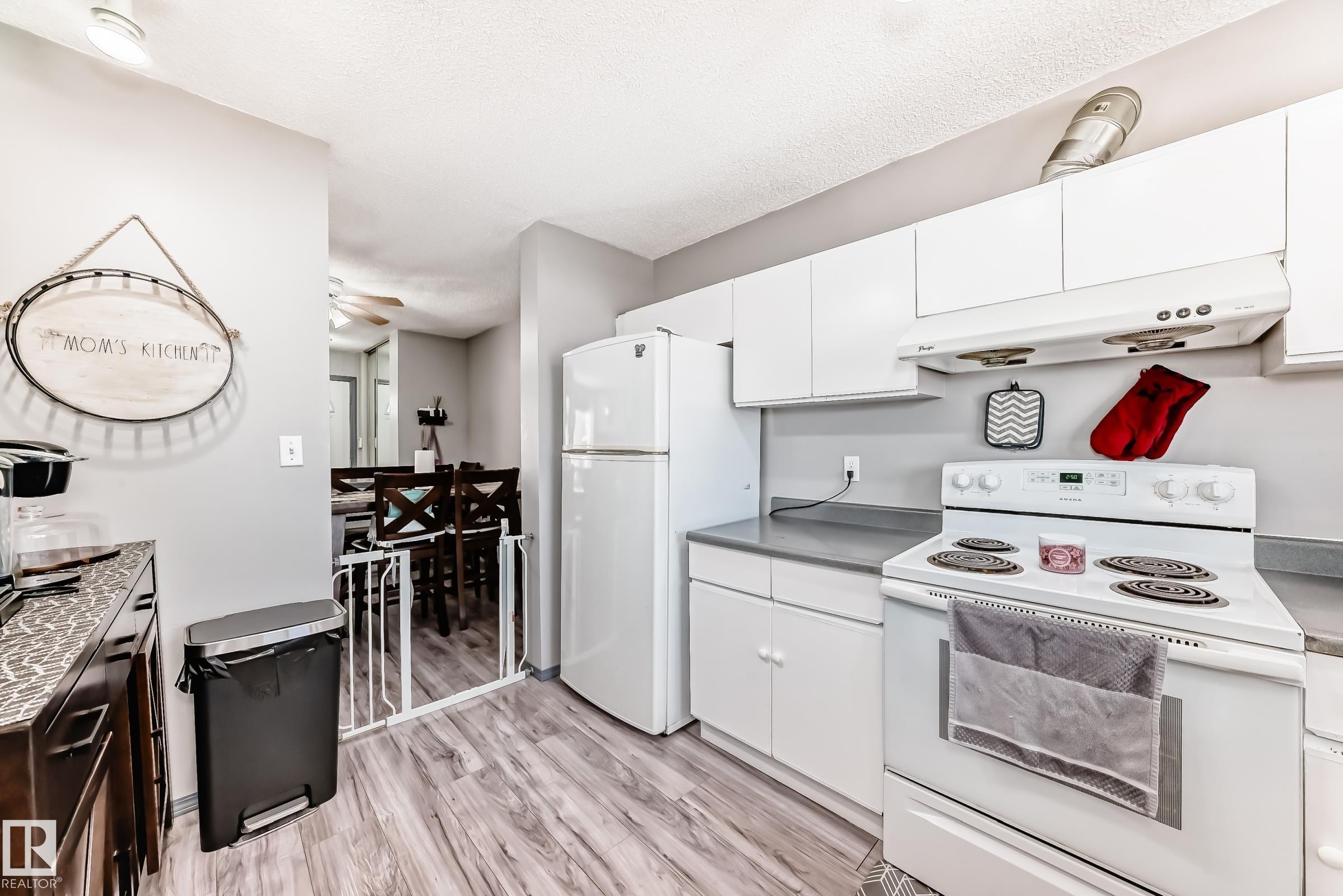 Kitchen with white appliances, white cabinetry, light wood-style flooring, light countertops, and a textured ceiling - 214A Warwick Road, Edmonton, AB - Indoor Photo Showing Kitchen