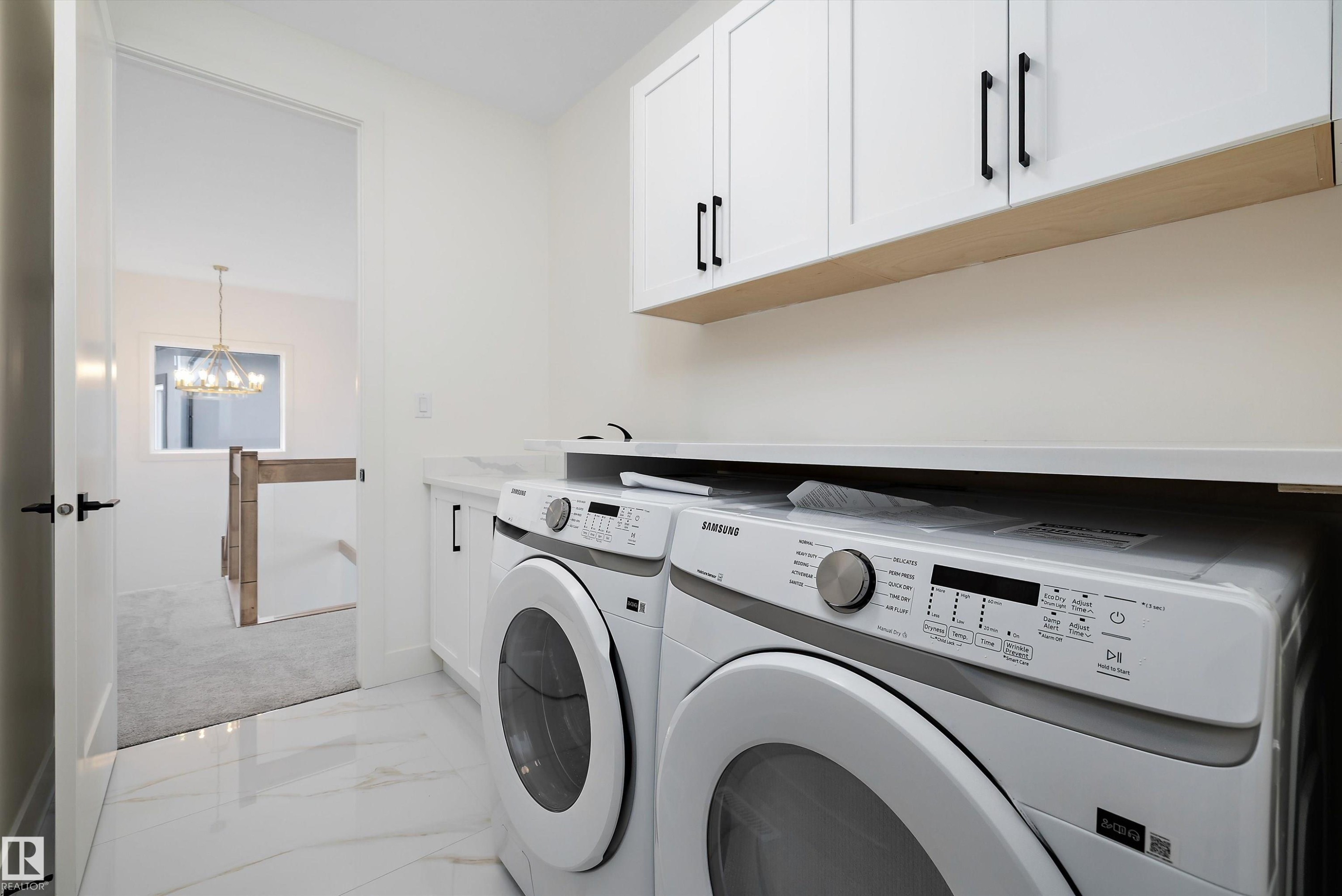 Laundry room with cabinet space, light marble finish floors, hanging lights, and washer and clothes dryer - 6871 Knox Loop Sw, Edmonton, AB - Indoor Photo Showing Laundry Room