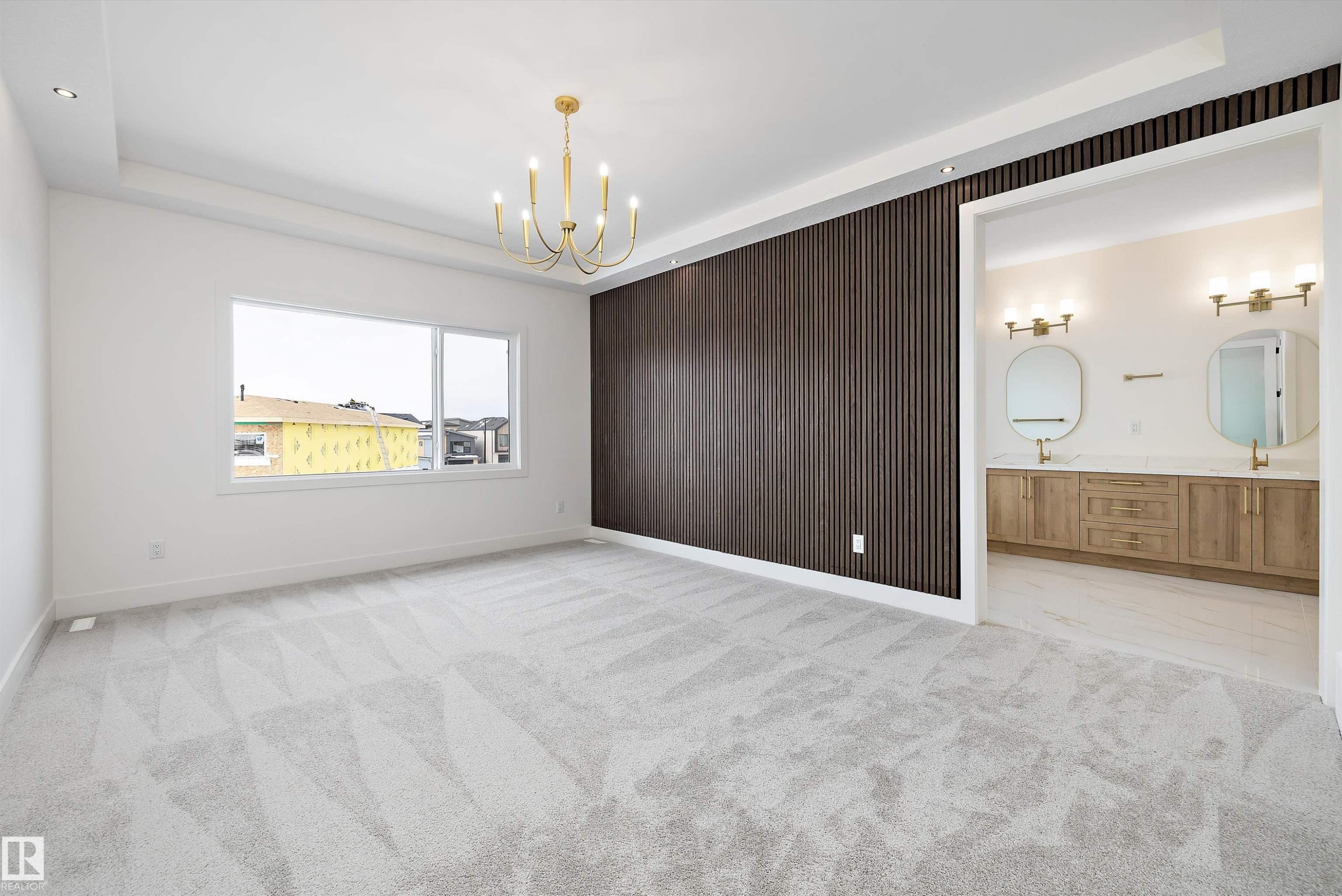 Empty room featuring light colored carpet, wooden walls, a raised ceiling, and a chandelier - 6871 Knox Loop Sw, Edmonton, AB - Indoor
