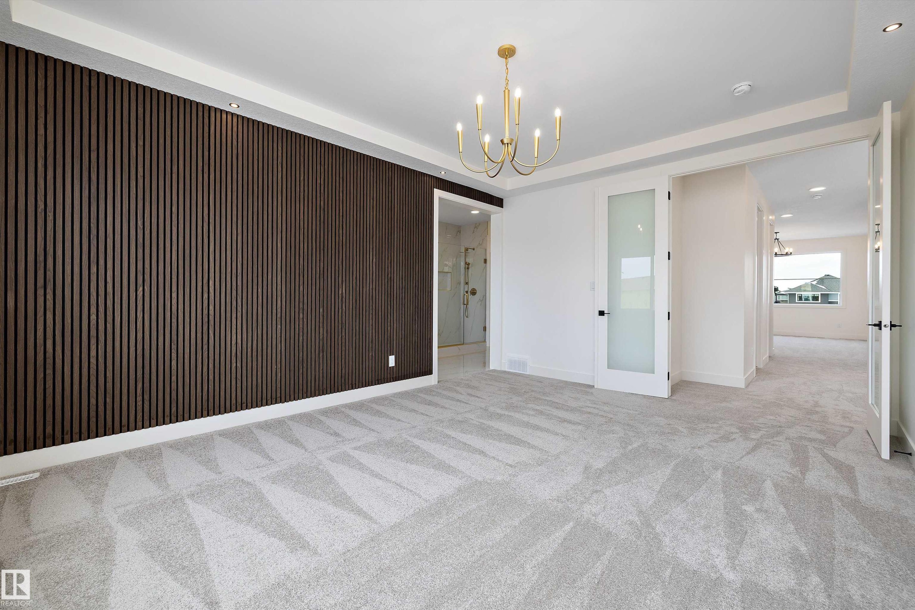 Spare room featuring hanging lights, light carpet, wooden walls, and a raised ceiling - 6871 Knox Loop Sw, Edmonton, AB - Indoor Photo Showing Other Room