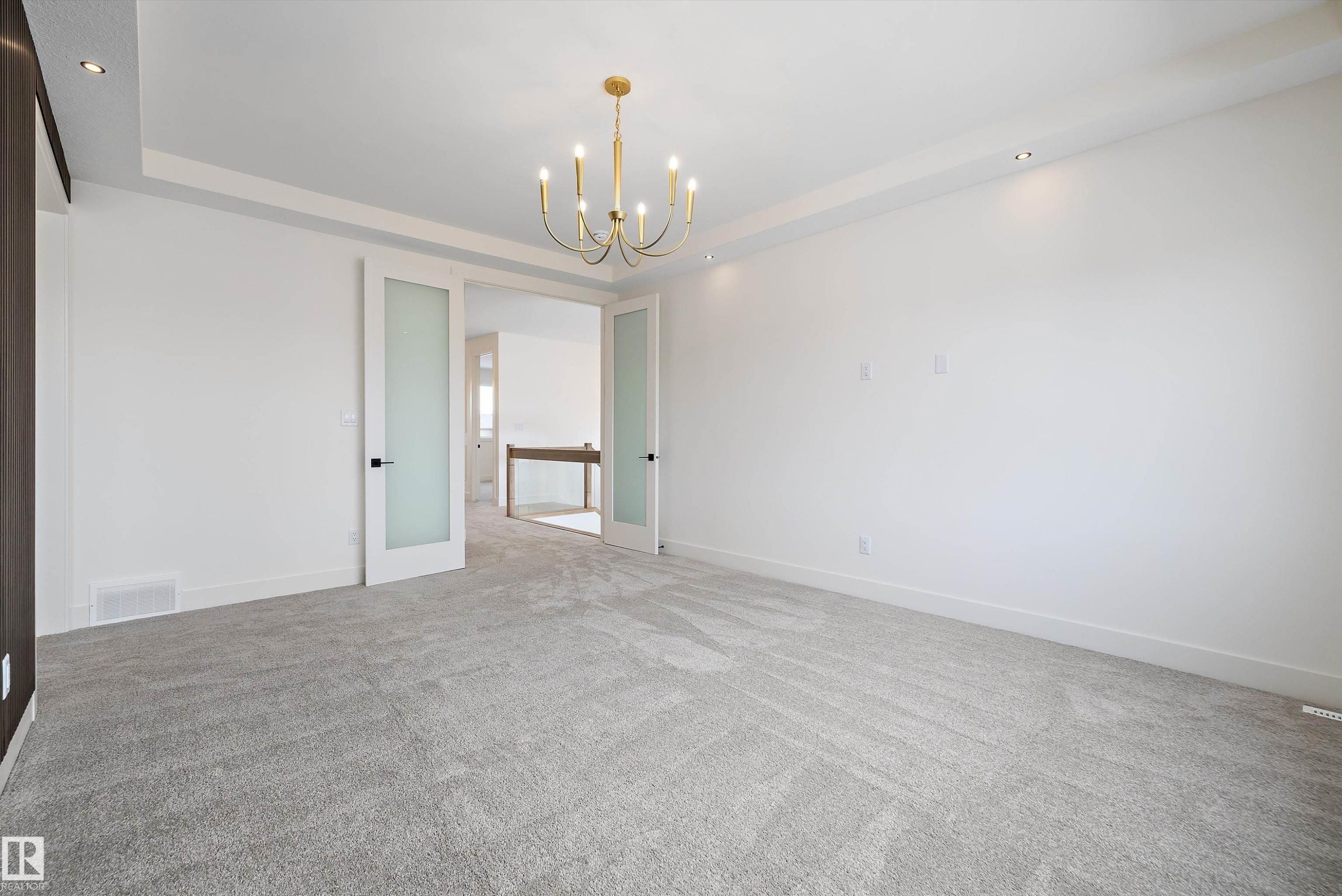 Spare room featuring suspended lighting, light colored carpet, and a raised ceiling - 6871 Knox Loop Sw, Edmonton, AB - Indoor Photo Showing Other Room