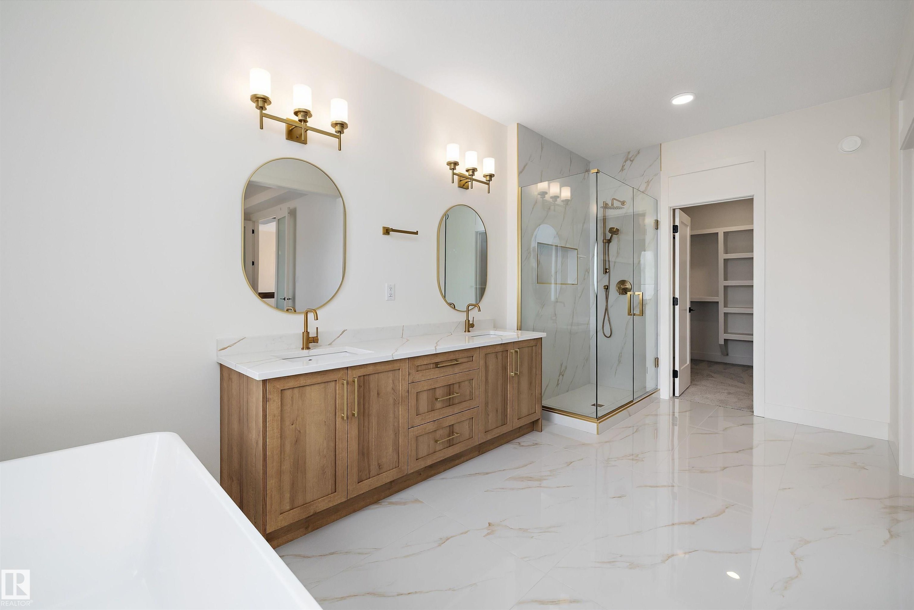 Bathroom featuring a freestanding bath, a walk in closet, a marble finish shower, double vanity, and light marble finish floors - 6871 Knox Loop Sw, Edmonton, AB - Indoor Photo Showing Bathroom