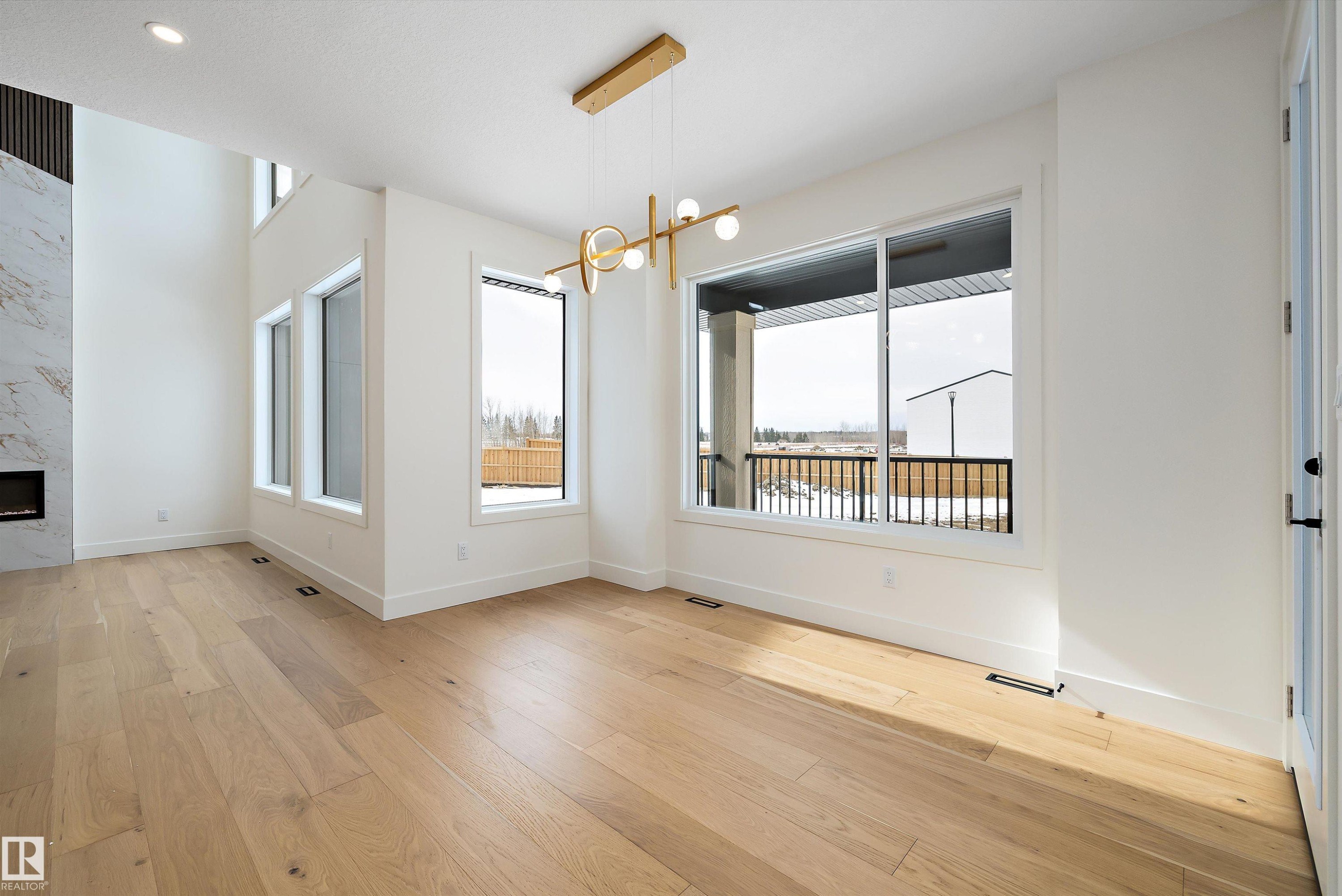 Unfurnished dining area featuring suspended lighting, a premium fireplace, and light wood-style flooring - 6871 Knox Loop Sw, Edmonton, AB - Indoor With Fireplace