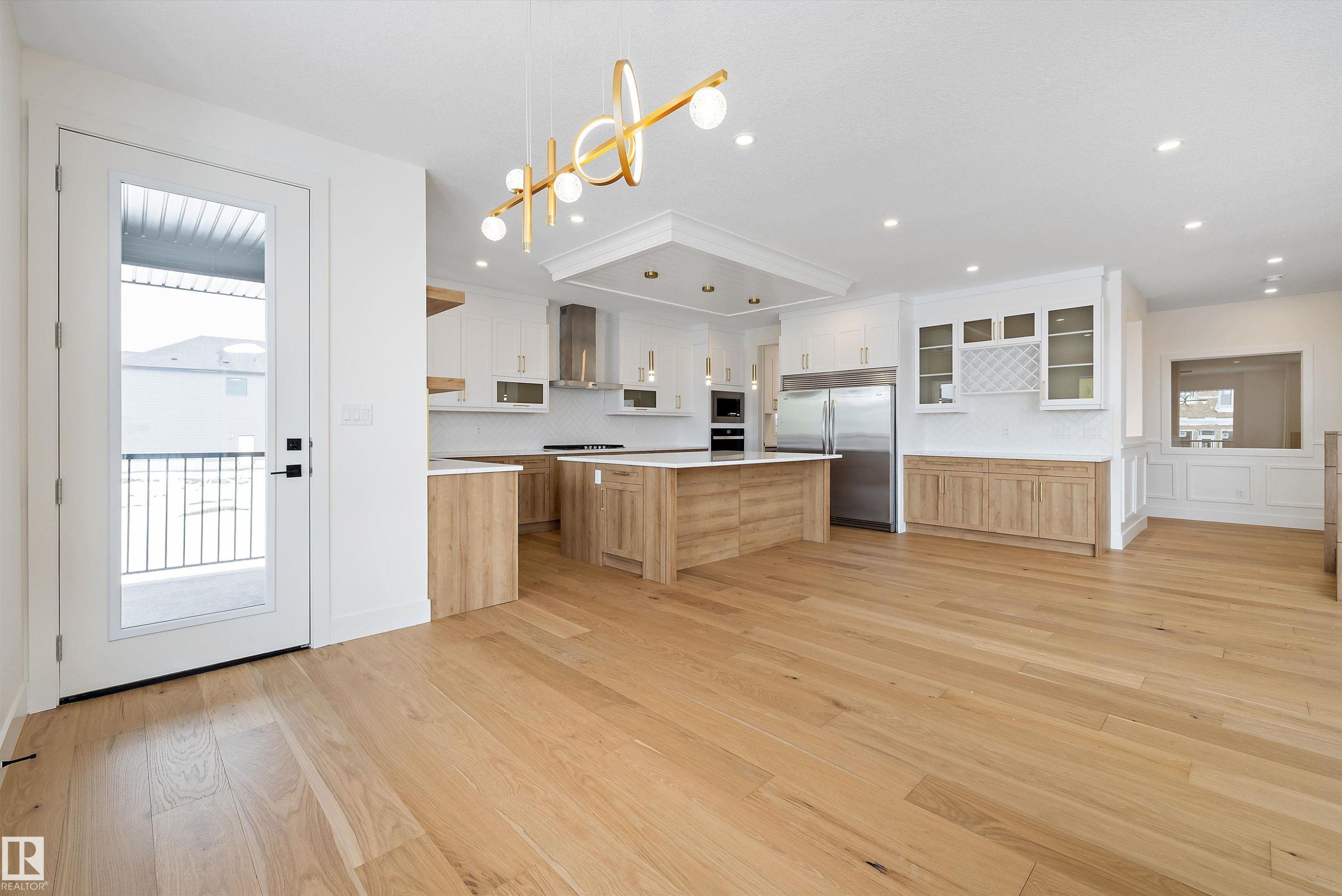 Two tone kitchen with a center island, built in appliances, glass insert cabinets, light wood finished floors, and two tone cabinets - 6871 Knox Loop Sw, Edmonton, AB - Indoor Photo Showing Kitchen