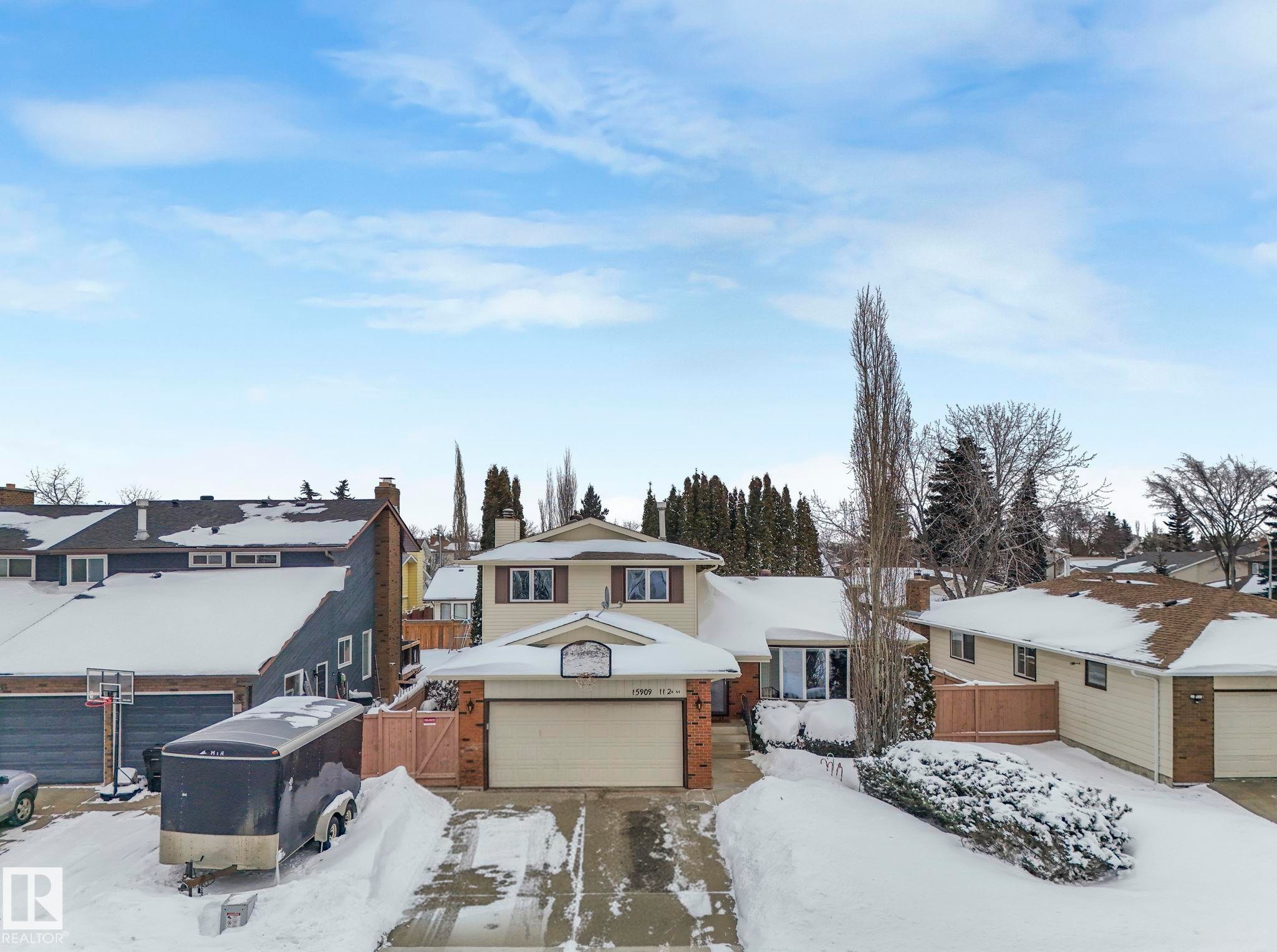 View of front of home featuring brick siding, a garage, a residential view, and a chimney - 15909 112 B Street Nw, Edmonton, AB - Outdoor