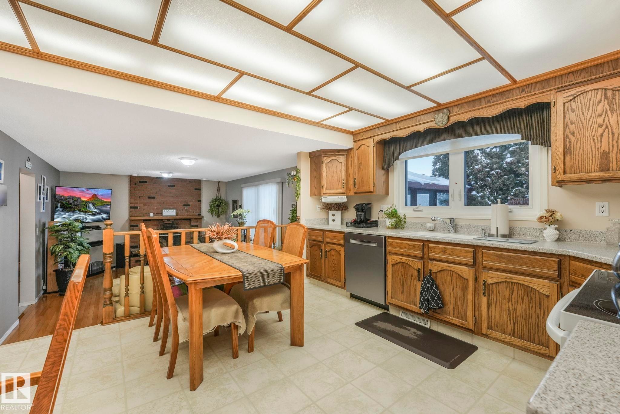 Kitchen featuring light countertops, wood finish cabinetry, dishwasher, electric range oven, and healthy amount of natural light - 15909 112 B Street Nw, Edmonton, AB - Indoor Photo Showing Kitchen