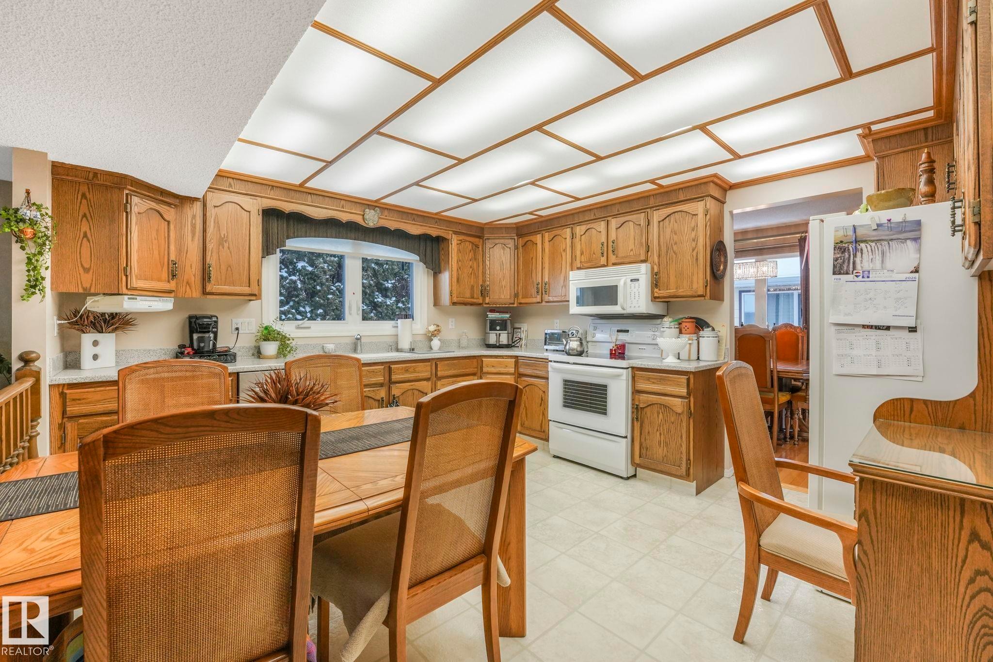 Kitchen with light countertops, white appliances, wood finish cabinetry, and light flooring - 15909 112 B Street Nw, Edmonton, AB - Indoor Photo Showing Kitchen