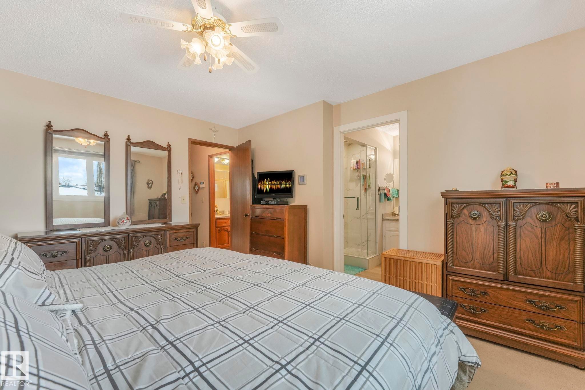Bedroom with light colored carpet, connected bathroom, and a ceiling fan - 15909 112 B Street Nw, Edmonton, AB - Indoor Photo Showing Bedroom