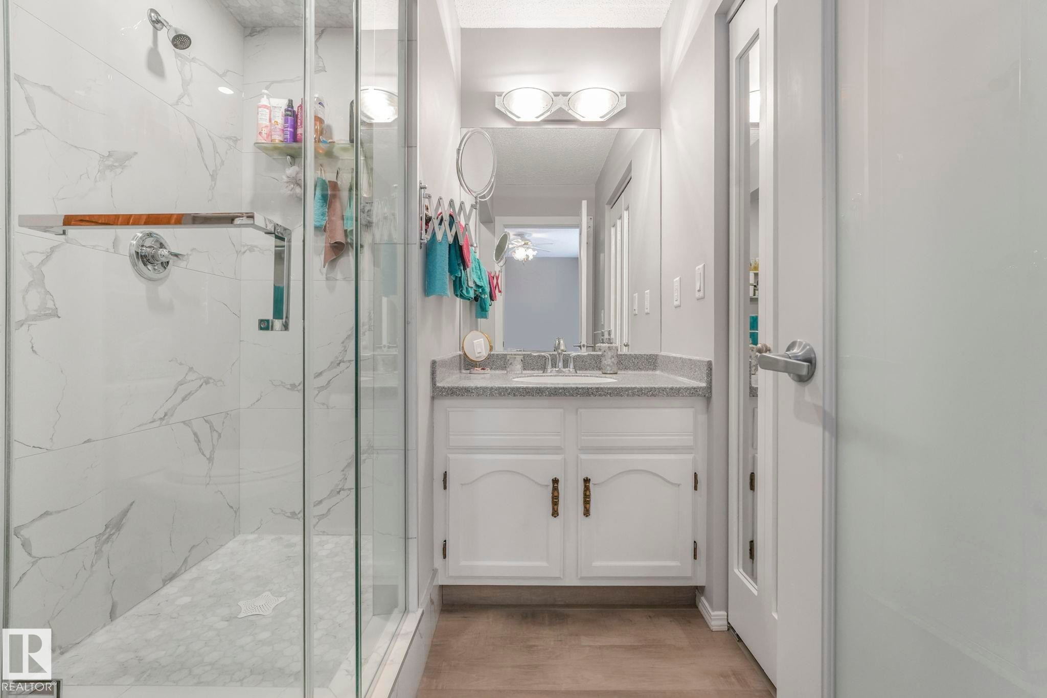 Bathroom featuring vanity, a marble finish shower, and light wood-type flooring - 15909 112 B Street Nw, Edmonton, AB - Indoor Photo Showing Bathroom