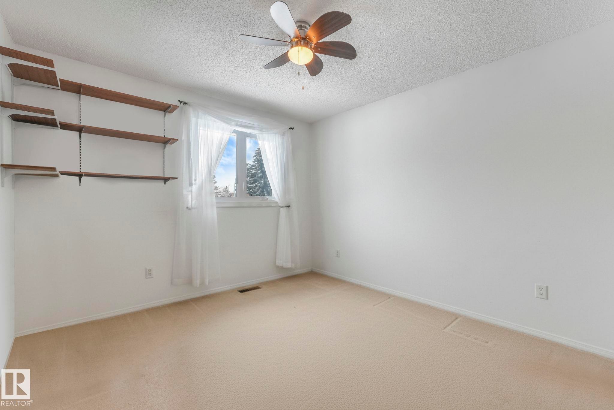 Empty room with light colored carpet, a ceiling fan, and a textured ceiling - 15909 112 B Street Nw, Edmonton, AB - Indoor Photo Showing Other Room