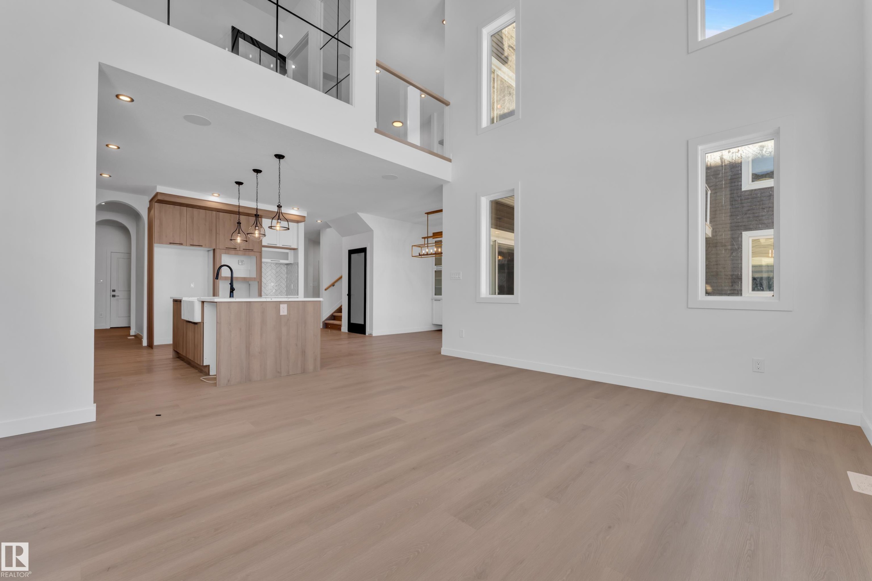 Unfurnished living room with arched walkways, a high ceiling, light wood-style floors, and a chandelier - 95 Eldridge Point(E), St. Albert, AB - Indoor