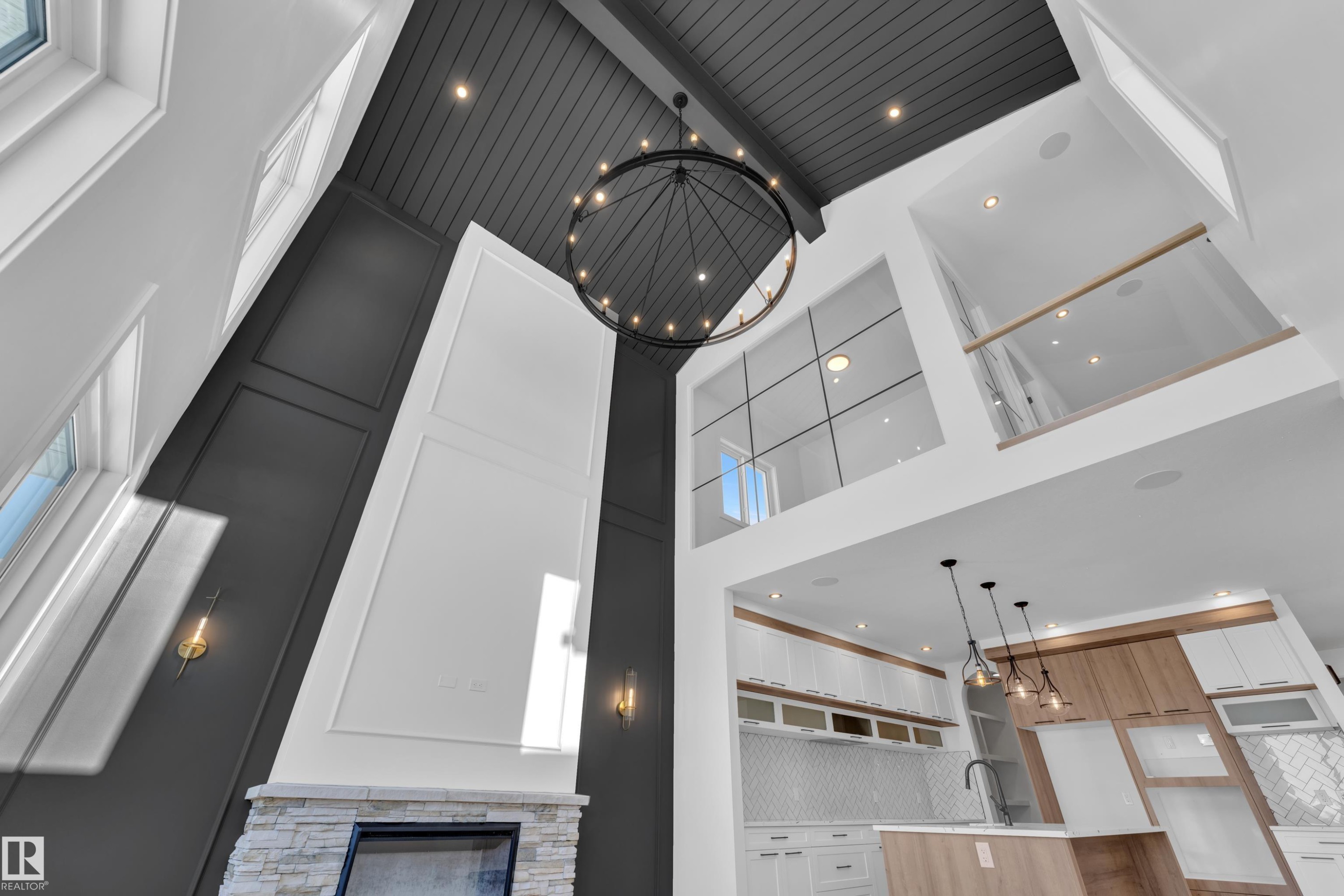 Kitchen view of hanging light fixtures, a stone fireplace, white cabinetry, open shelves, and light stone counters - 95 Eldridge Point(E), St. Albert, AB -