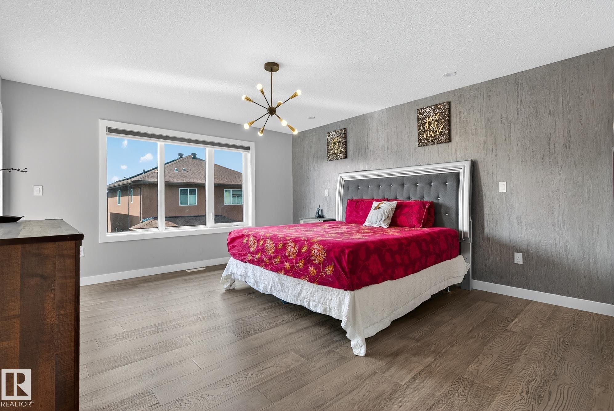 Bedroom with an accent wall, wood finished floors, suspended lighting, and a textured ceiling - 1027 150 Avenue, Edmonton, AB - Indoor Photo Showing Bedroom