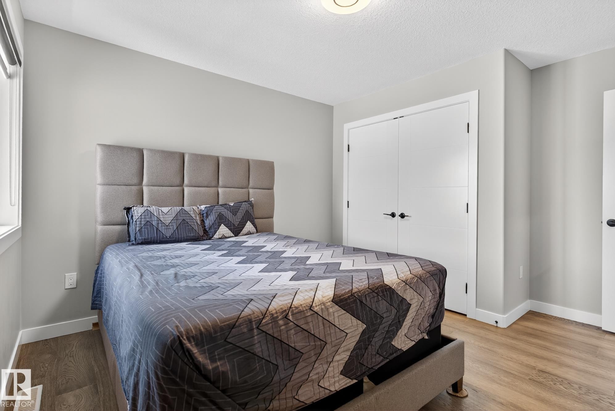 Bedroom with a closet, wood finished floors, and a textured ceiling - 1027 150 Avenue, Edmonton, AB - Indoor Photo Showing Bedroom