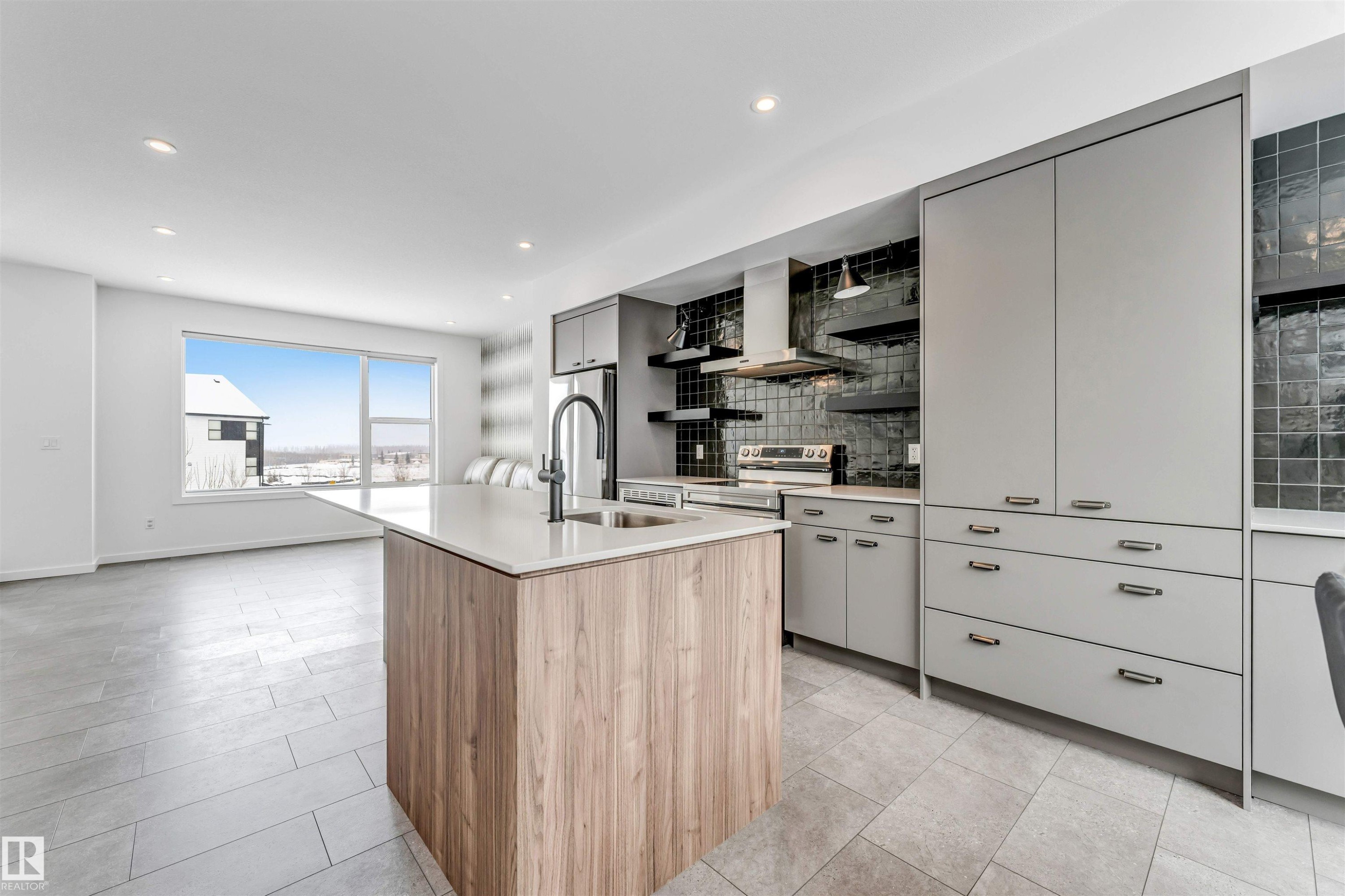 Two tone kitchen with two tone color scheme, a center island with sink, backsplash, open shelves, and modern cabinets - 77 5 Rondeau Drive, St. Albert, AB - Indoor Photo Showing Kitchen With Upgraded Kitchen