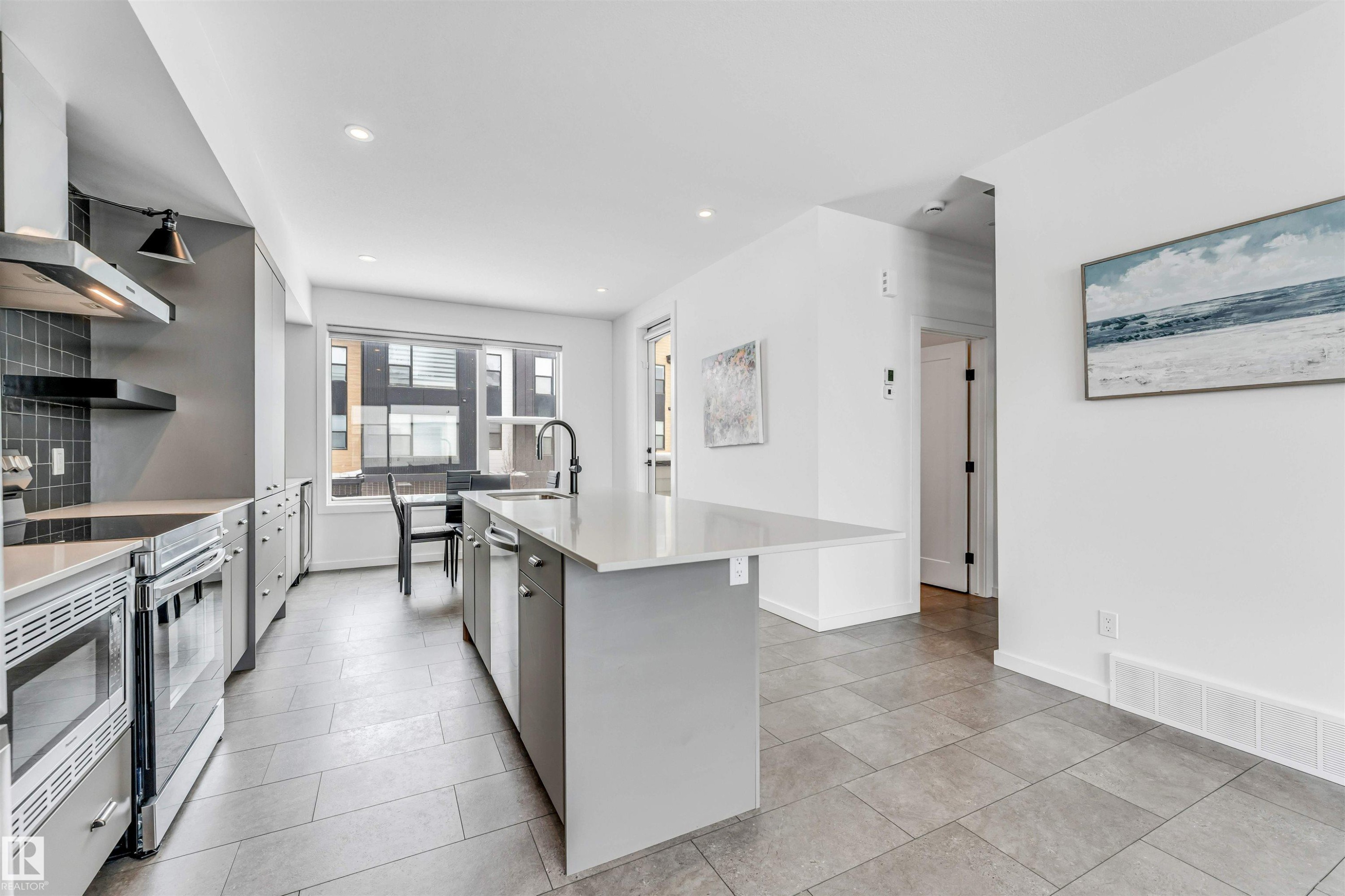 Kitchen with an island with sink, stainless steel appliances, open shelves, tasteful backsplash, and light stone counters - 77 5 Rondeau Drive, St. Albert, AB - Indoor Photo Showing Kitchen With Upgraded Kitchen