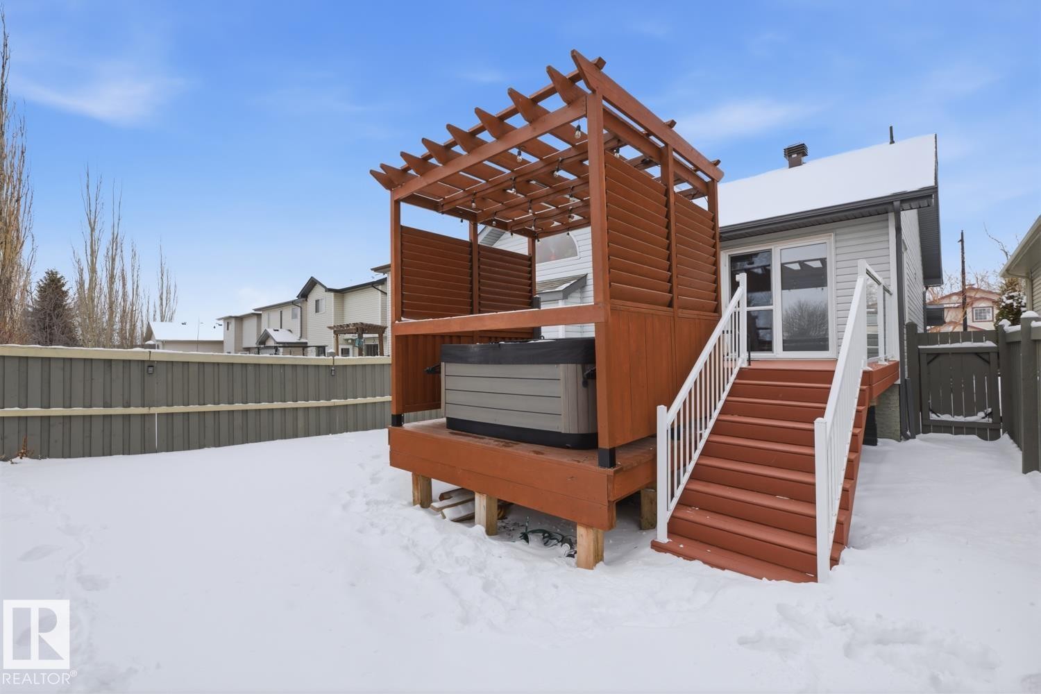 Snow covered house with a fenced backyard, a gate, a deck, and a hot tub - 20148 46 Avenue, Edmonton, AB - Outdoor