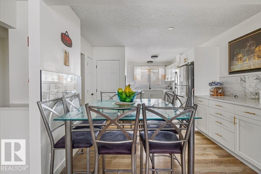 Dining area with a textured ceiling and light wood-style floors - 13211 71 Street, Edmonton, AB - Indoor Photo Showing Dining Room