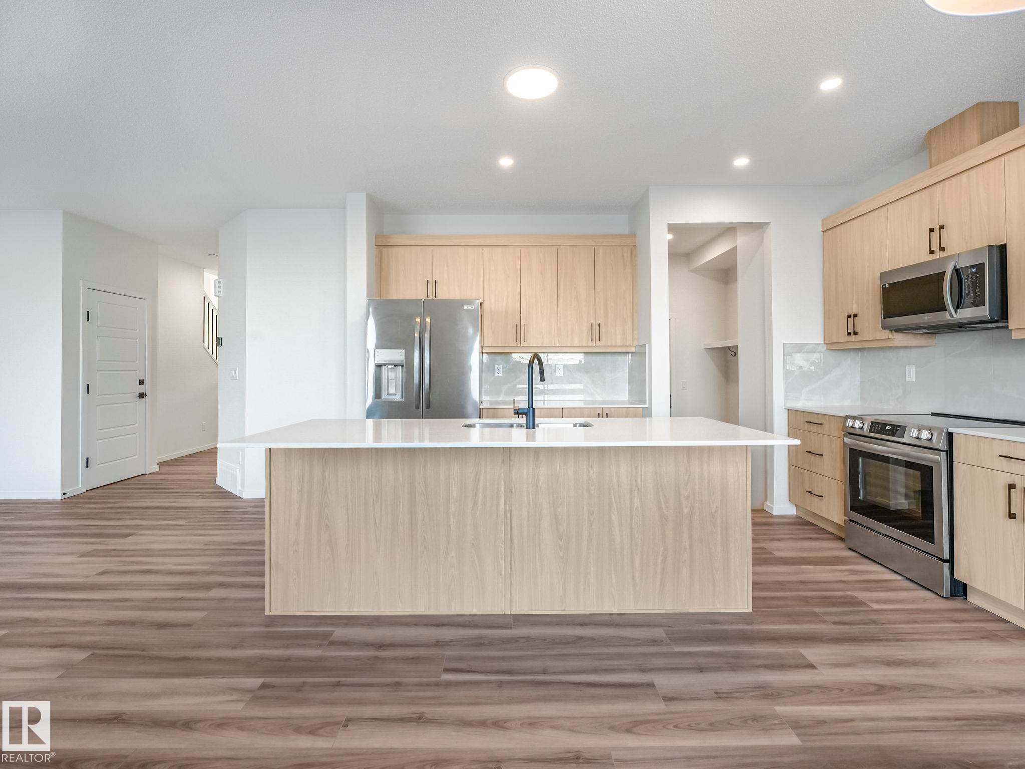 Kitchen featuring light wood finish cabinetry, stainless steel appliances, light wood finished floors, decorative backsplash, and recessed lighting - 20506 16A Avenue, Edmonton, AB - Indoor Photo Showing Kitchen