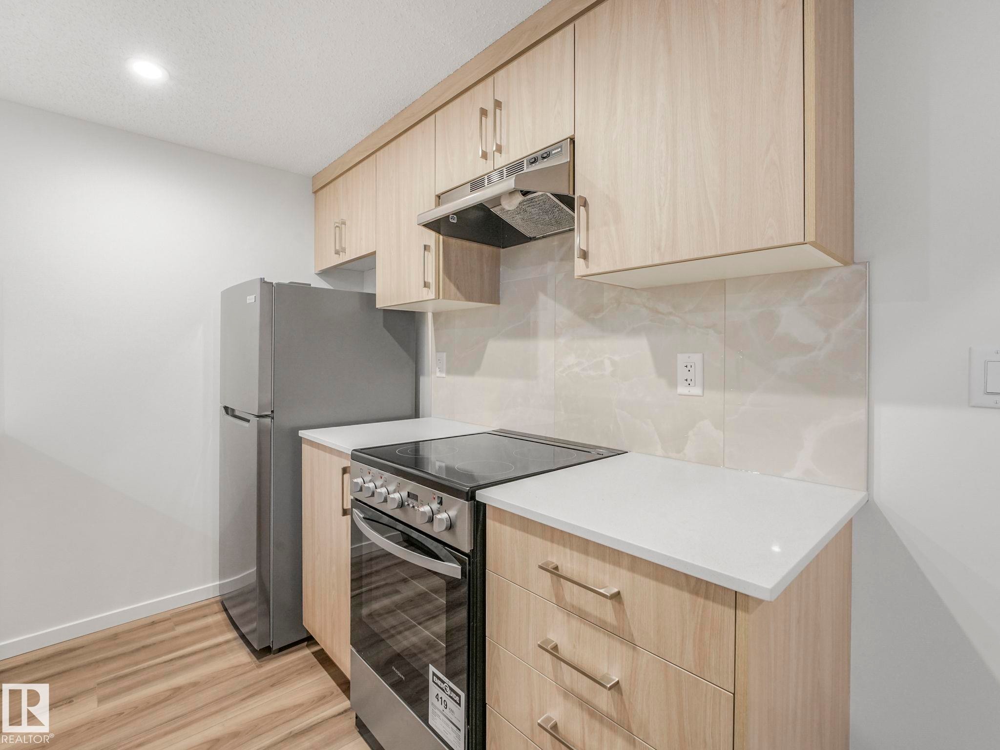 Kitchen featuring light wood finish cabinetry, stainless steel electric range oven, modern cabinets, light wood-style flooring, and recessed lighting - 20506 16A Avenue, Edmonton, AB - Indoor Photo Showing Kitchen