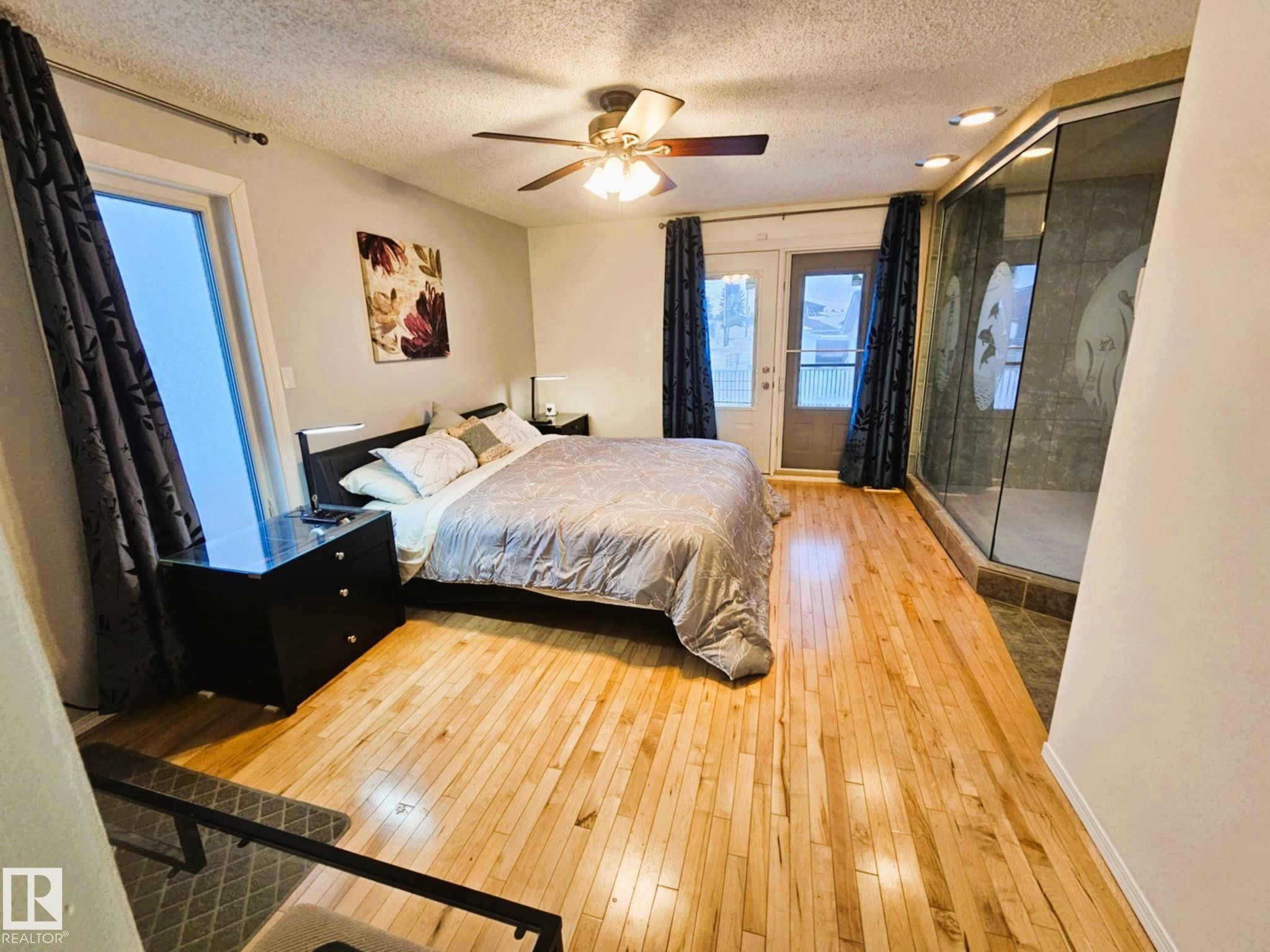 Bedroom with light wood-style floors, a textured ceiling, access to outside, and ceiling fan - 8512 131 Avenue, Edmonton, AB - Indoor Photo Showing Bedroom